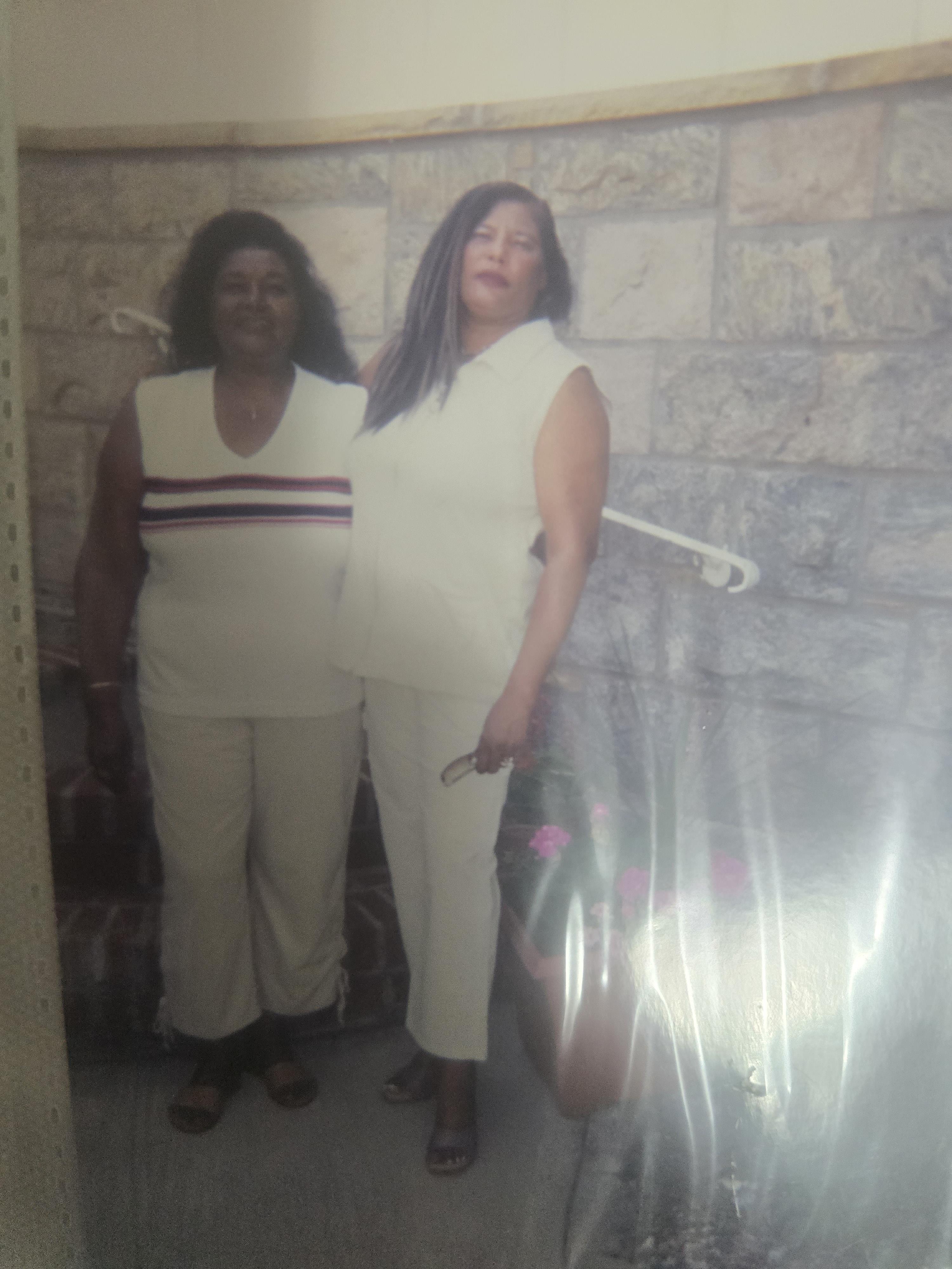 Two women stand side by side, smiling together in a relaxed atmosphere during the day.