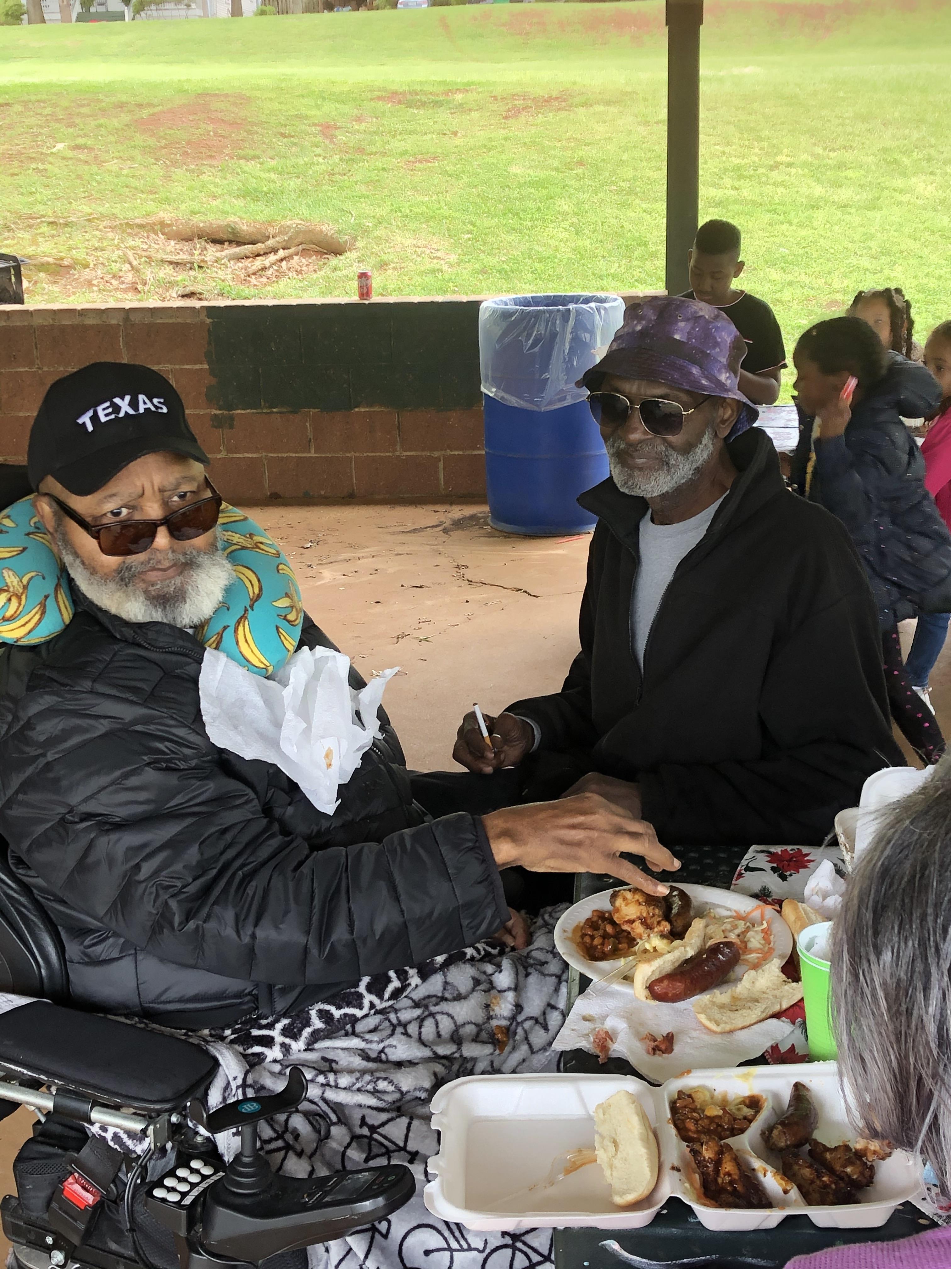 Two friends share a meal at a park, enjoying each other's company and good food together.