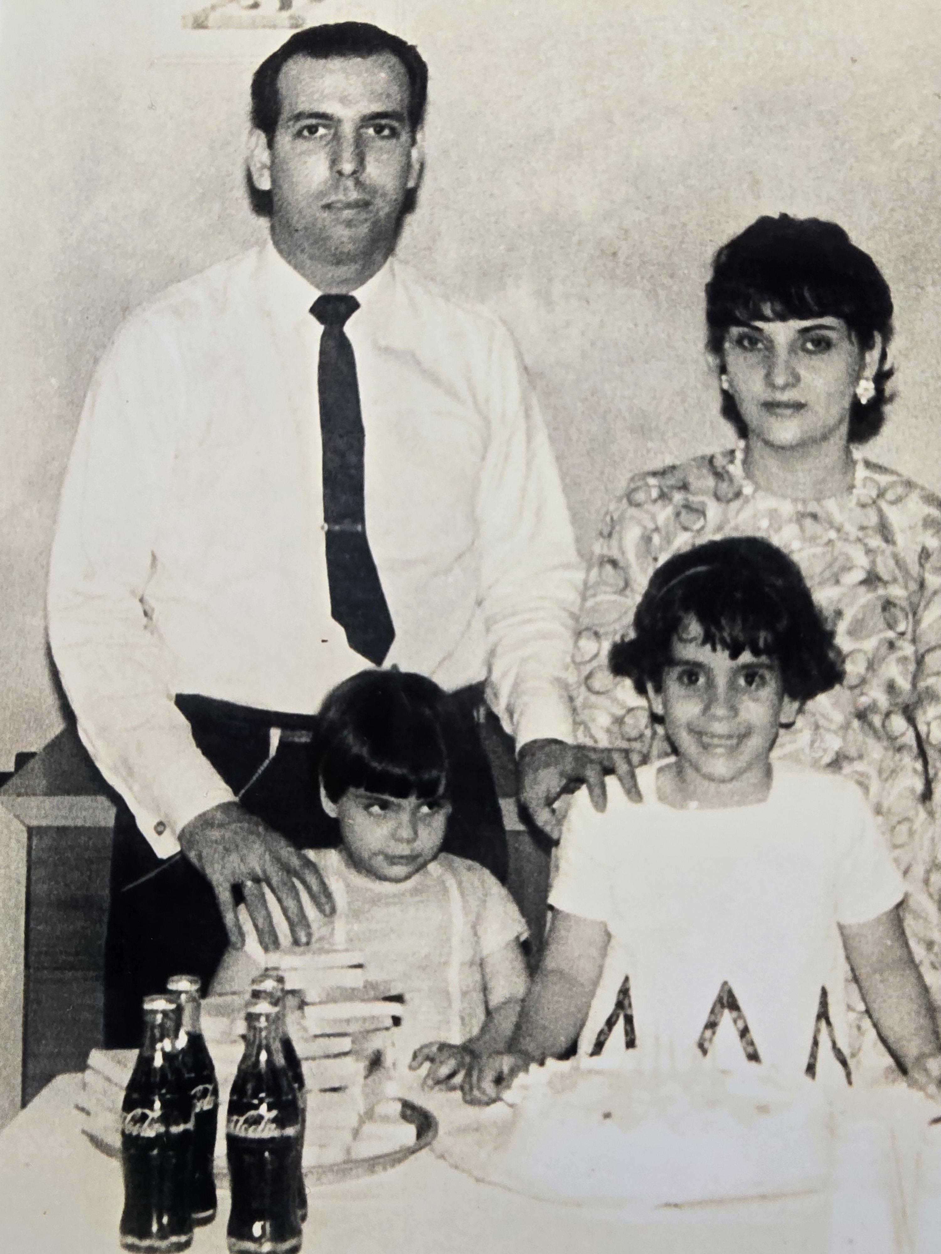 A family celebrates a special occasion together with drinks and a birthday cake.