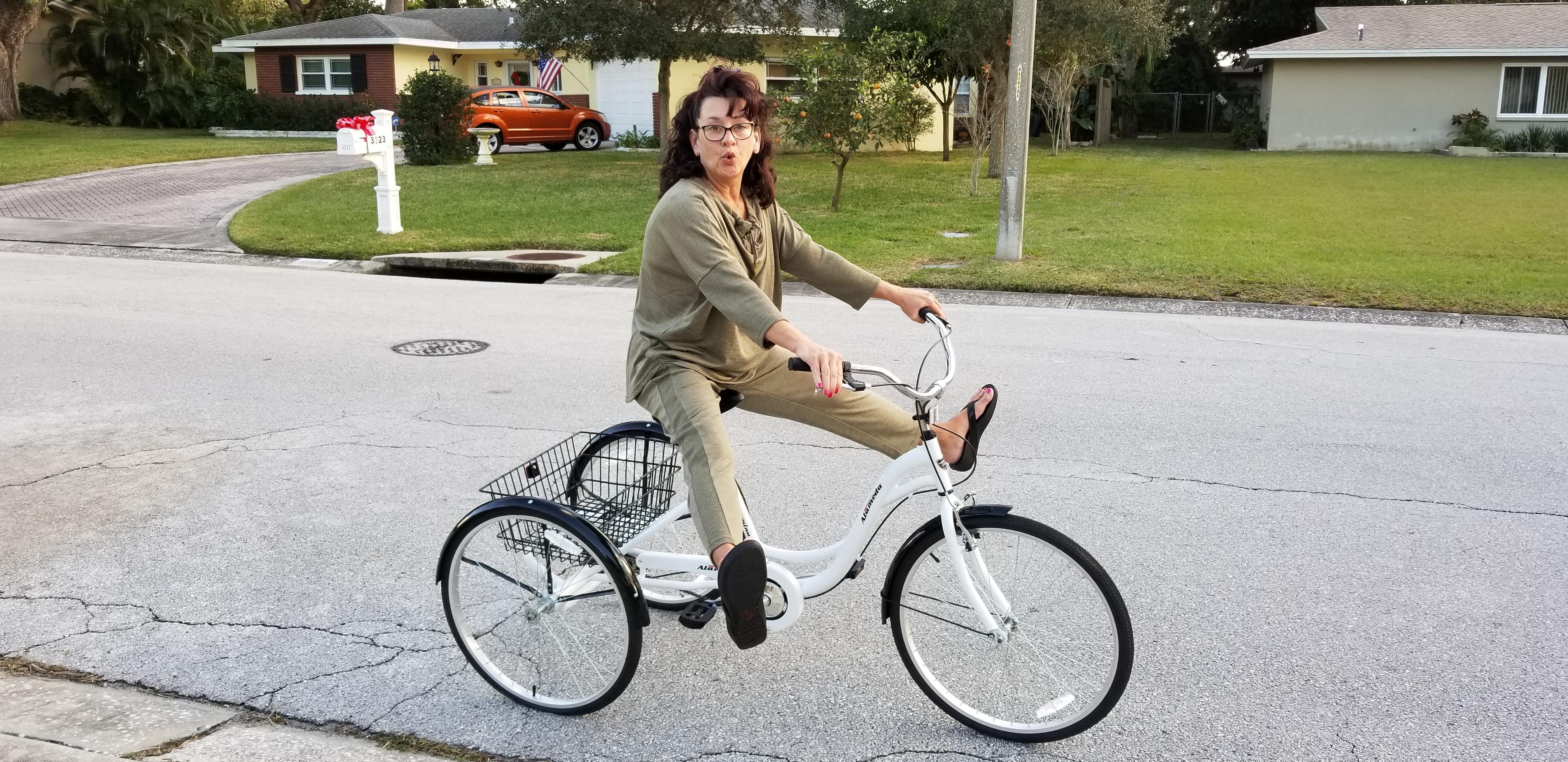 A girl is joyfully riding a bicycle down a quiet suburban street, surrounded by greenery.