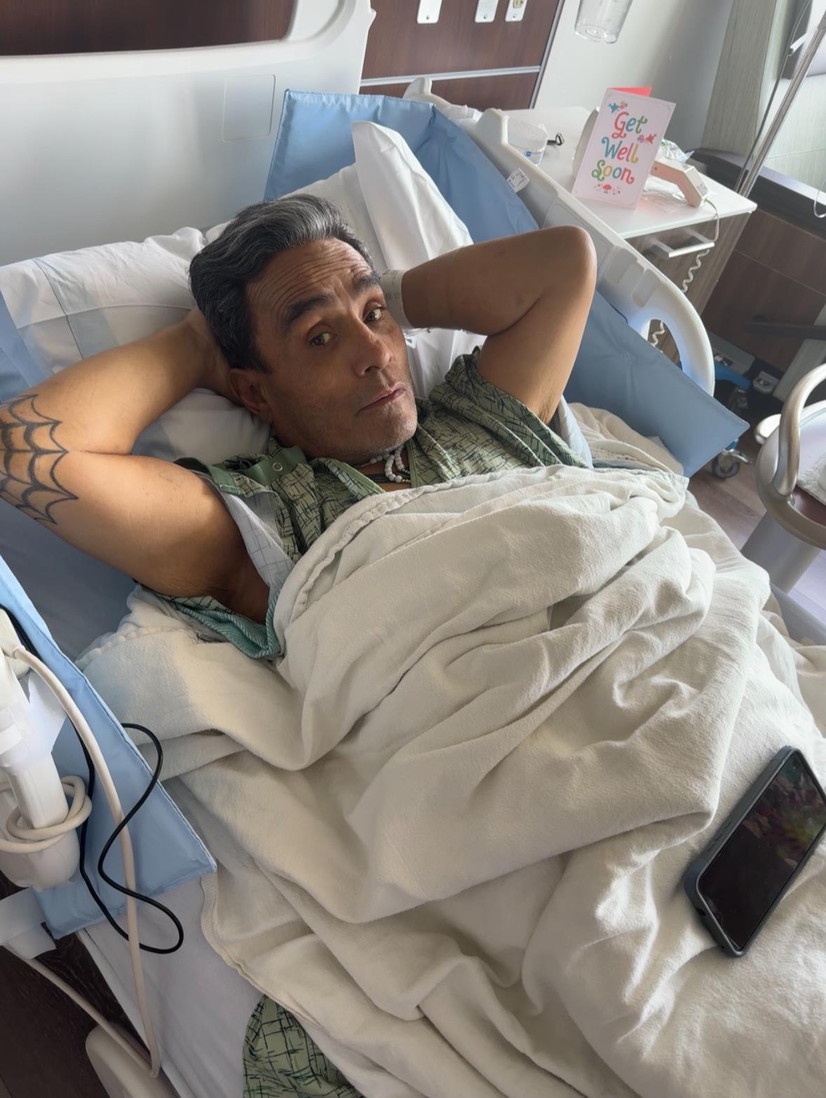Patient relaxes in bed, wearing a hospital gown, surrounded by supportive medical environment.