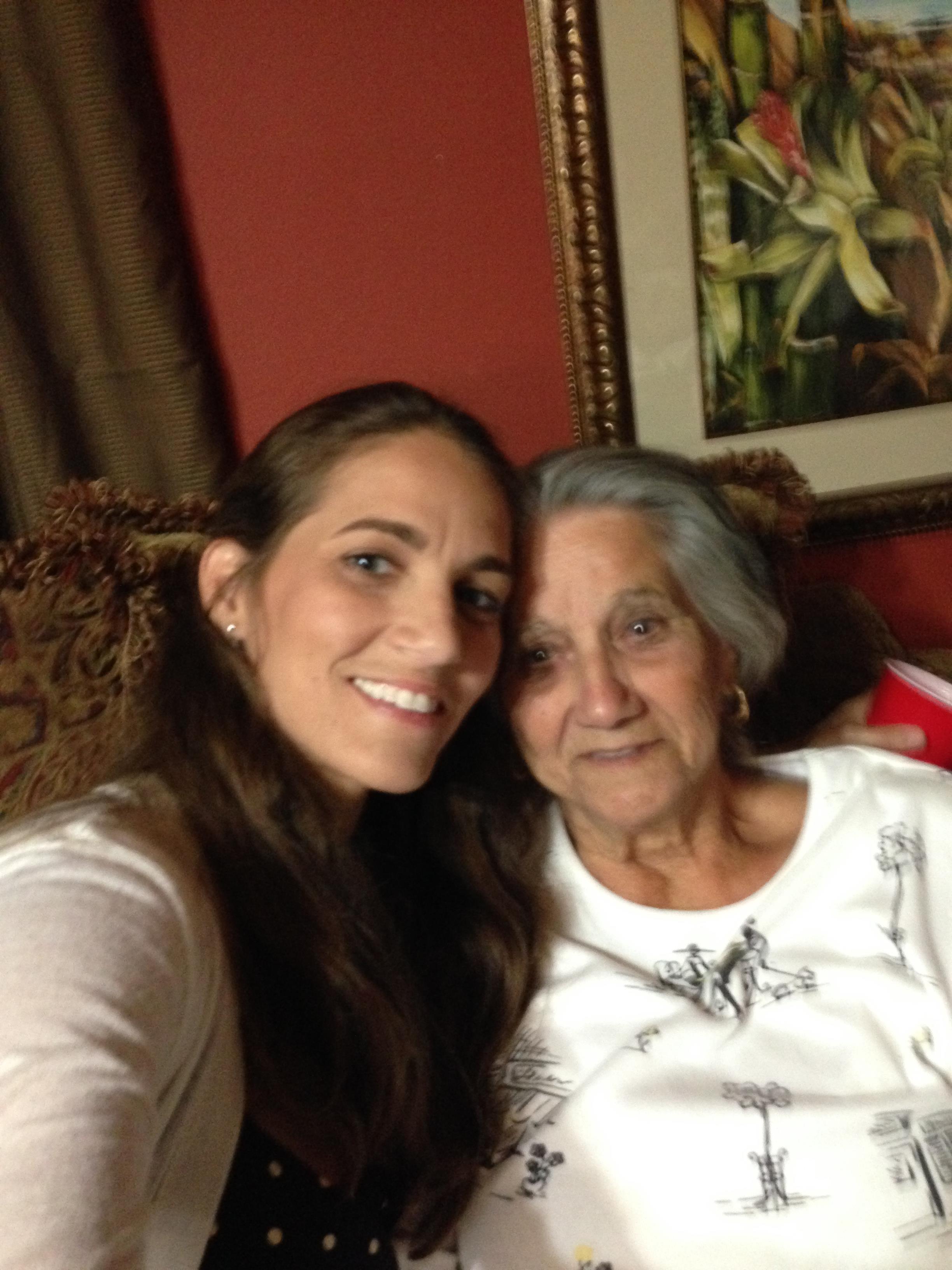 Two family members are smiling together while resting on a comfortable couch in a warm living room.