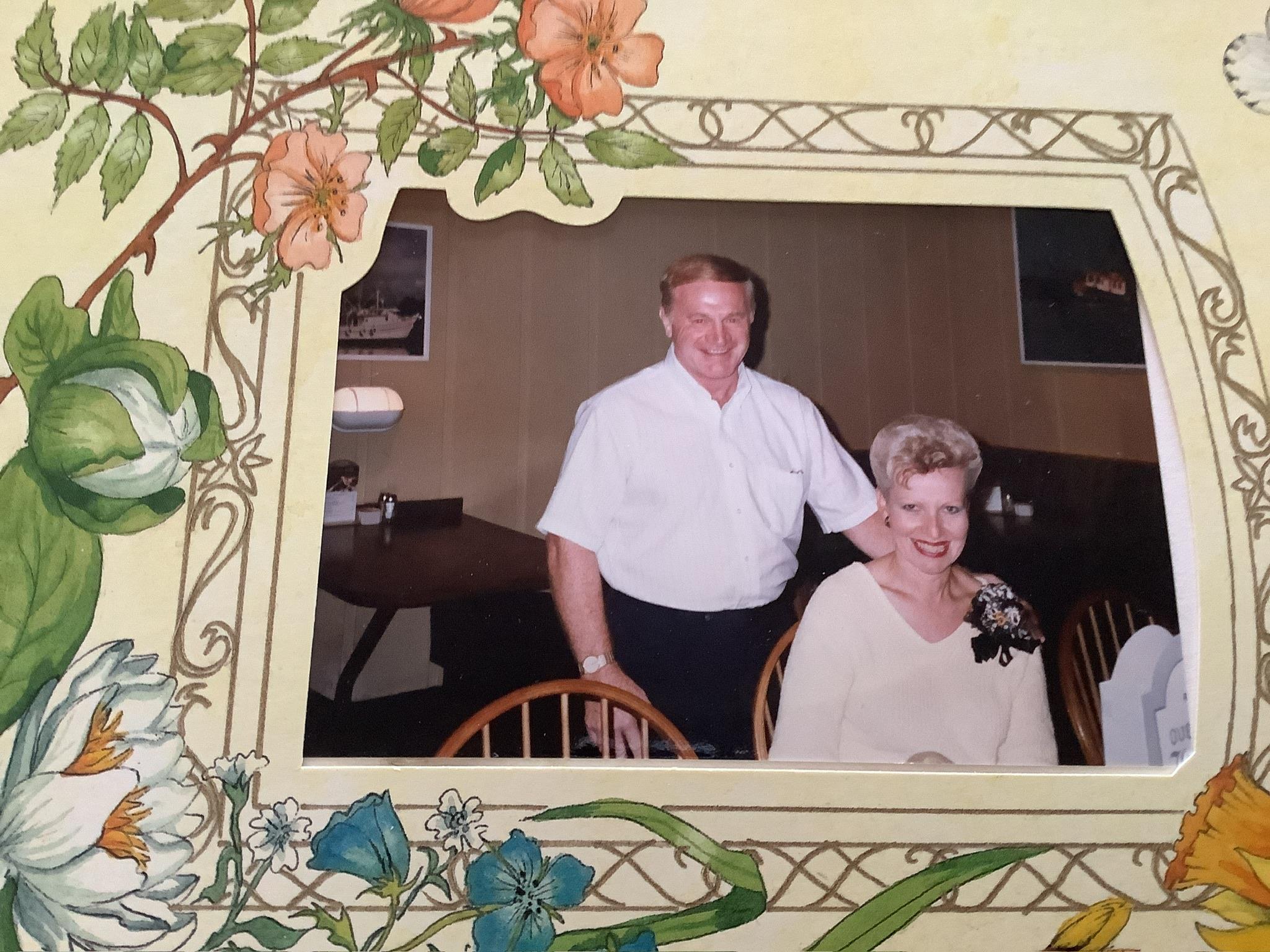 A couple smiles warmly while seated at a dinner table, surrounded by a charming decor.