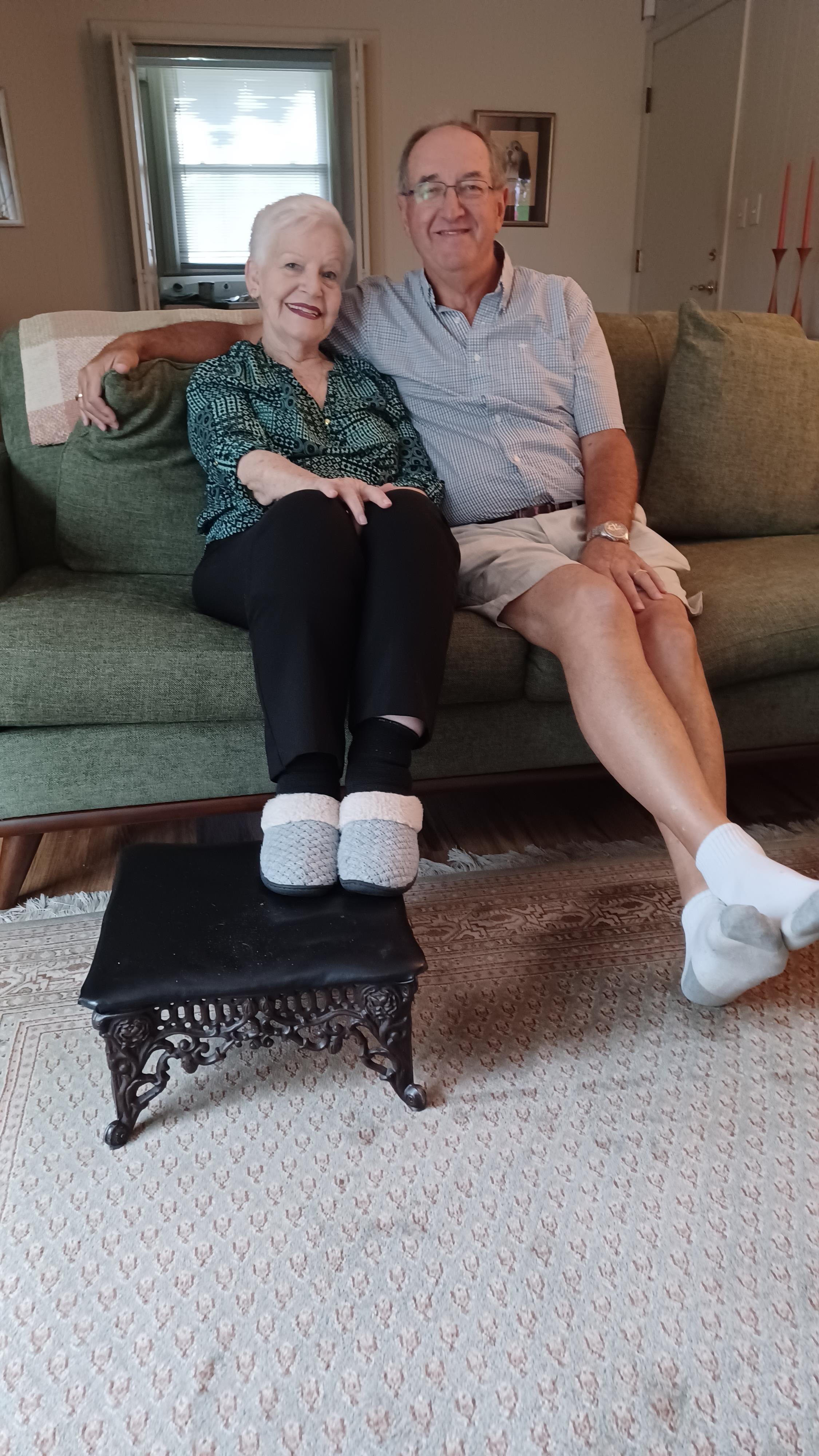 A couple sits comfortably on a couch, sharing smiles in their welcoming living space.