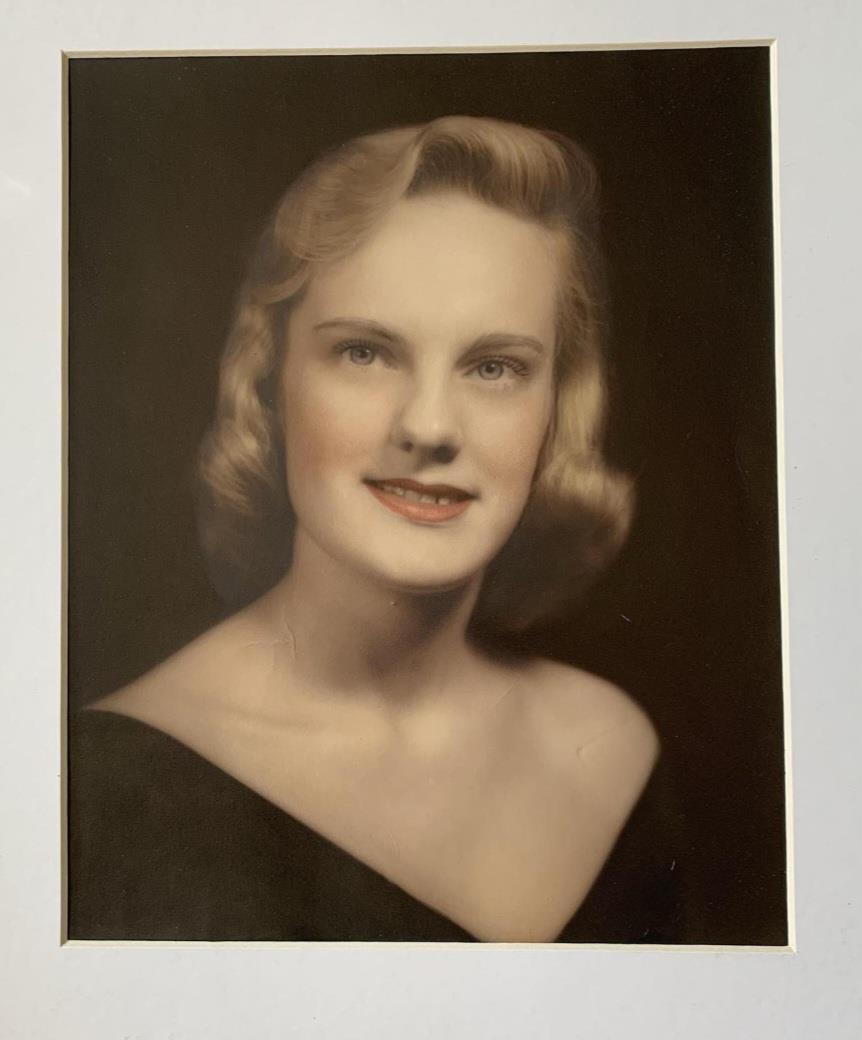 A young woman in a shoulder-baring dress smiles warmly, showcasing vintage beauty and style.
