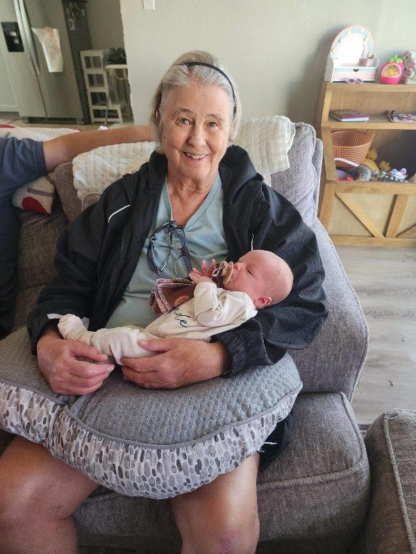 Smiling elderly woman cradles an infant in a cozy living room, highlighting family togetherness.