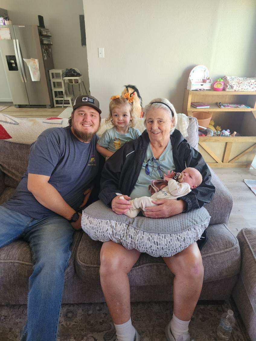 Grandparent enjoys quality time with grandchildren on a comfortable couch in the living room.