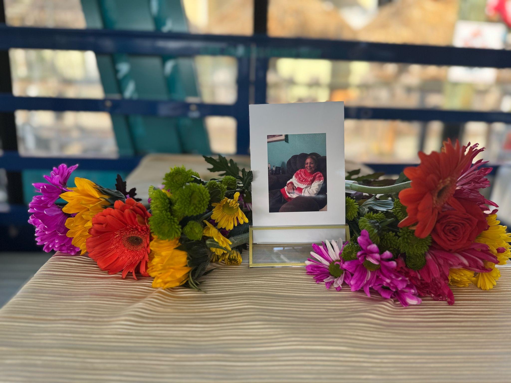 Colorful flowers frame a picture on a table, celebrating life and cherished memories.