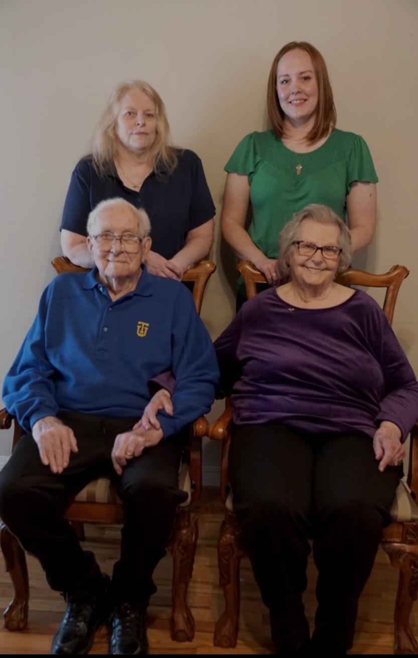 Four family members sit together, sharing smiles and warmth in a cozy home environment.