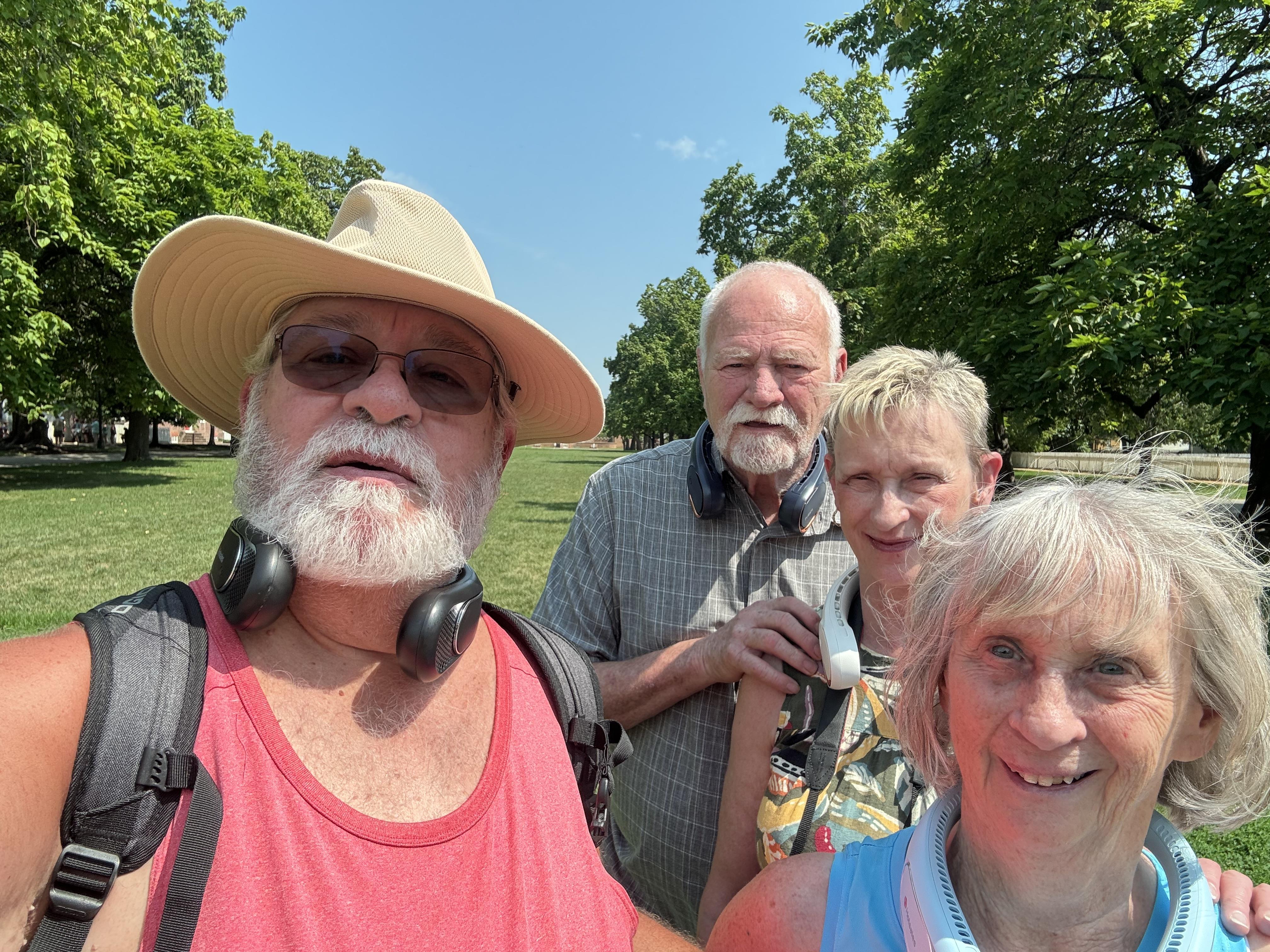 Four people are gathered outdoors under the bright sun, clearly enjoying their time together.