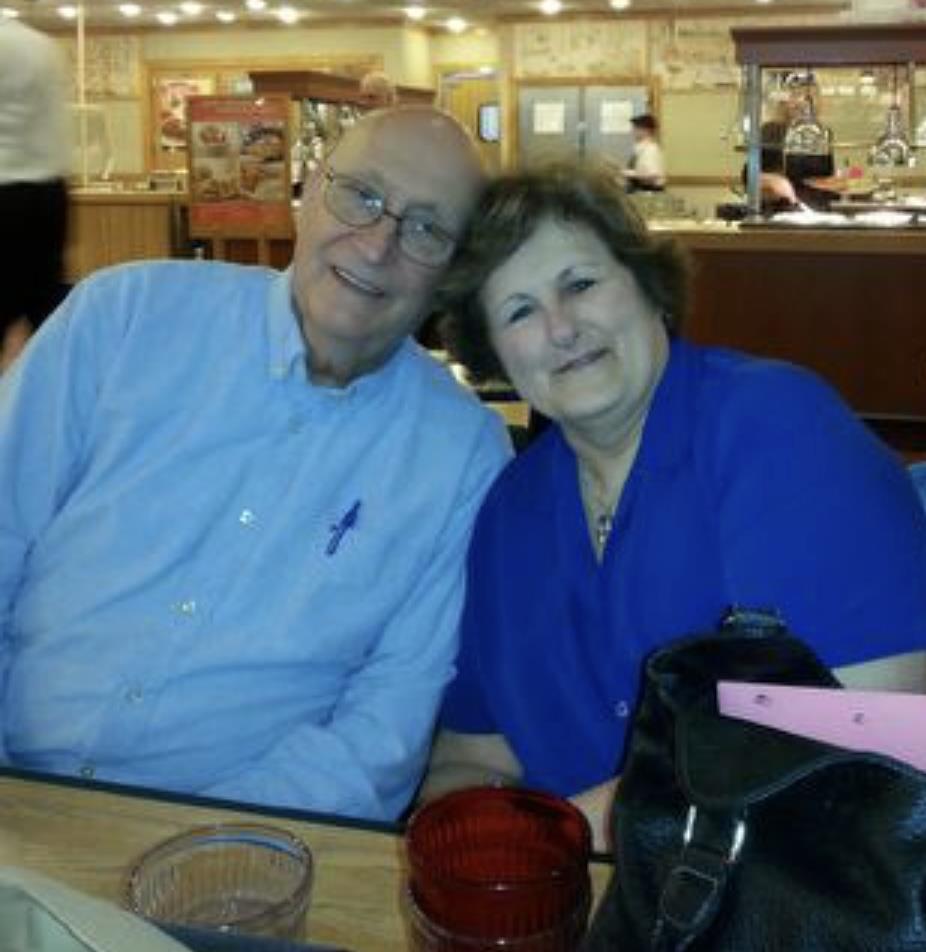 Two smiling individuals sit at a restaurant table, enjoying their time together in a casual setting.