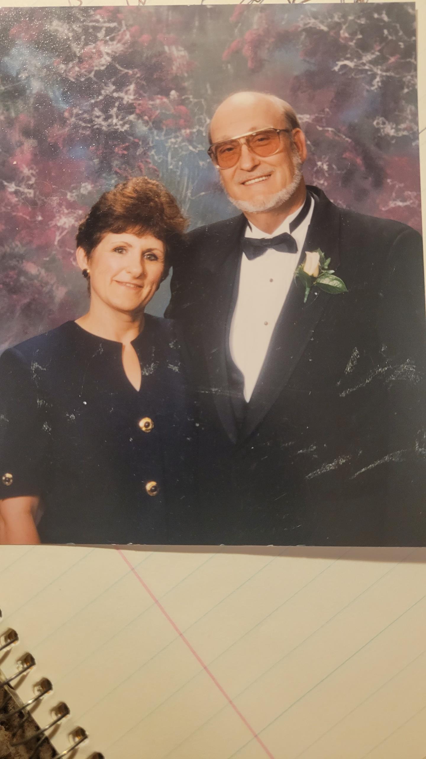 A couple is happily posing in formal wear at a festive gathering. They exude joy and elegance.