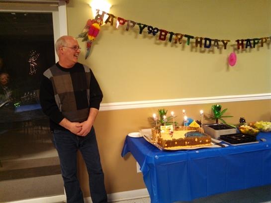 A man standing next to a table with a cake and candles