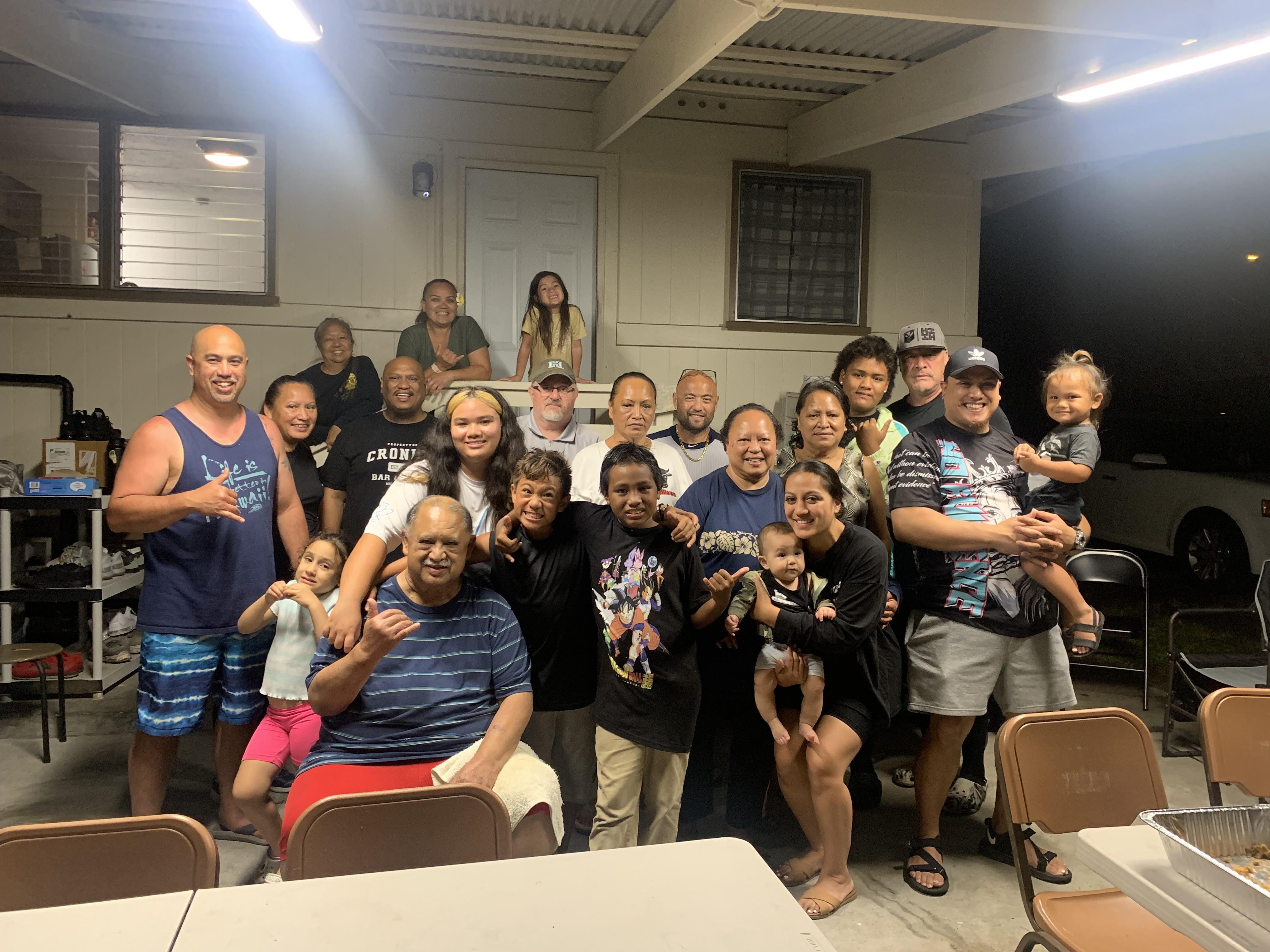 Many family members gather at a community center for a joyful celebration with food and smiles.