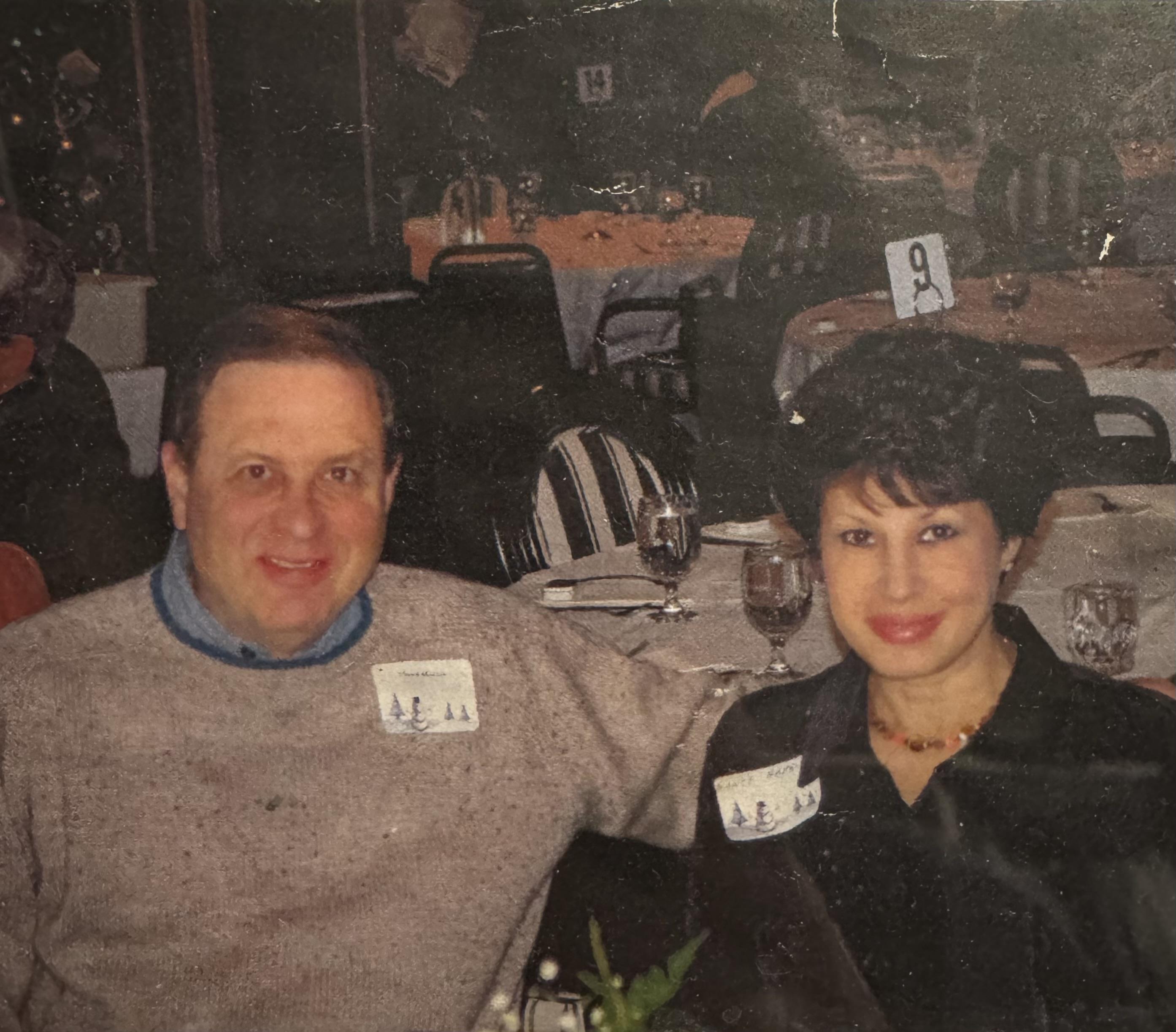 A couple sits closely together at a restaurant table, enjoying their evening meal.