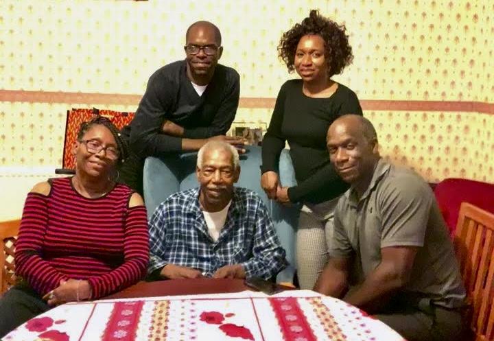 Five family members enjoy quality time together, sitting at a table in a warm home environment.