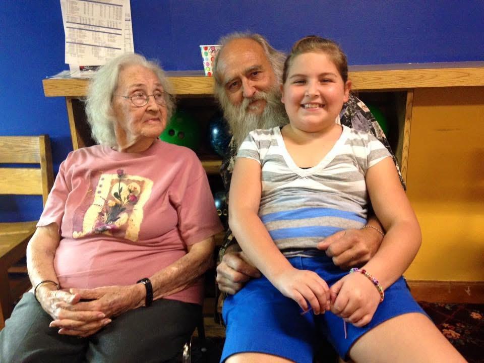 Three generations enjoy quality time together in a colorful bowling alley setting.