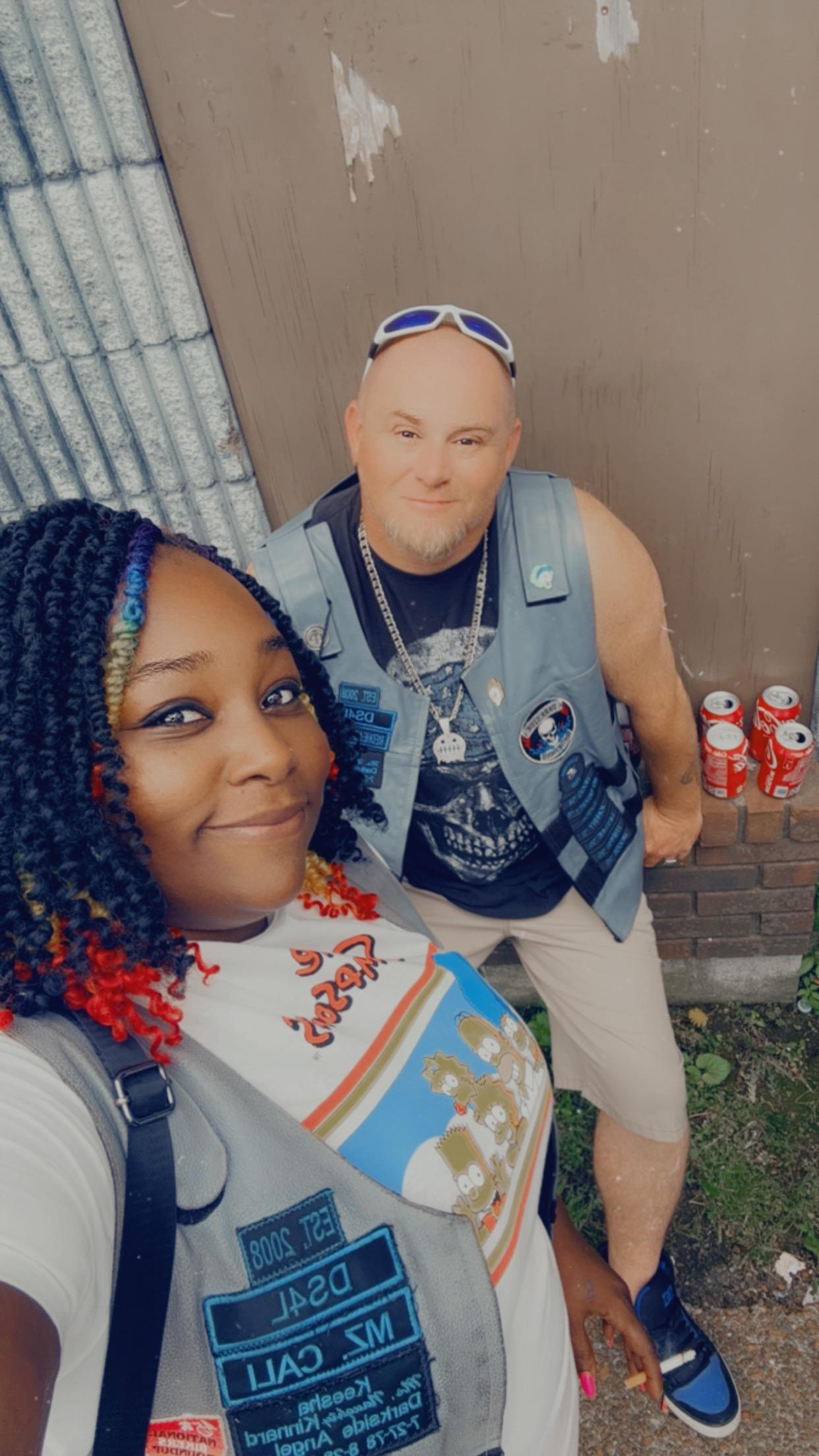 Two friends pose together in a vibrant atmosphere, smiling and having a good time outdoors.