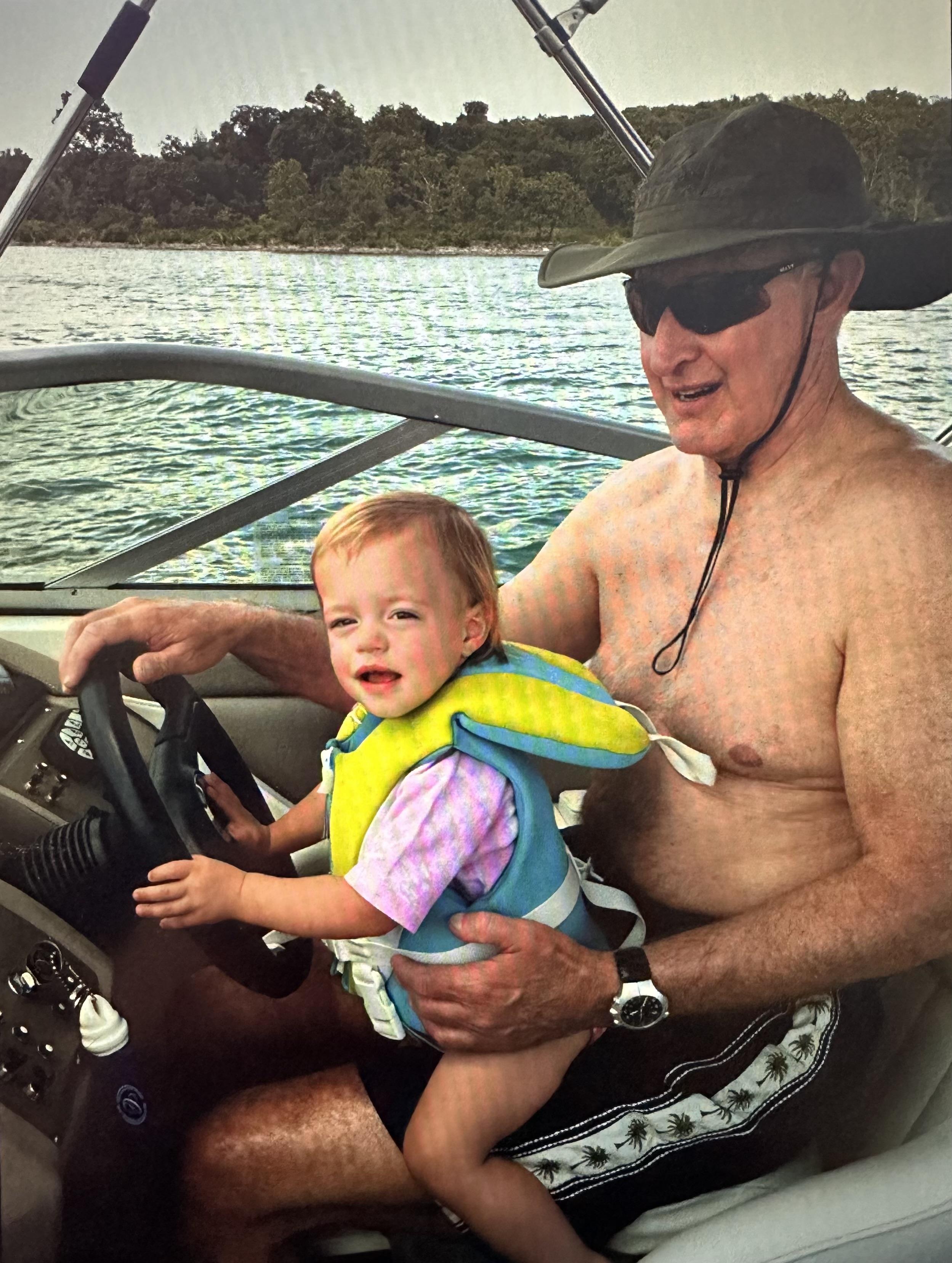 A cheerful grandfather and his young granddaughter are enjoying a boat ride together.