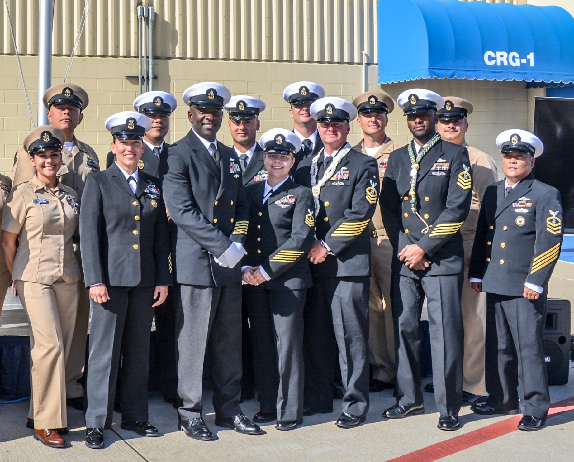 Military personnel of various ranks gathered outside a facility under clear skies.