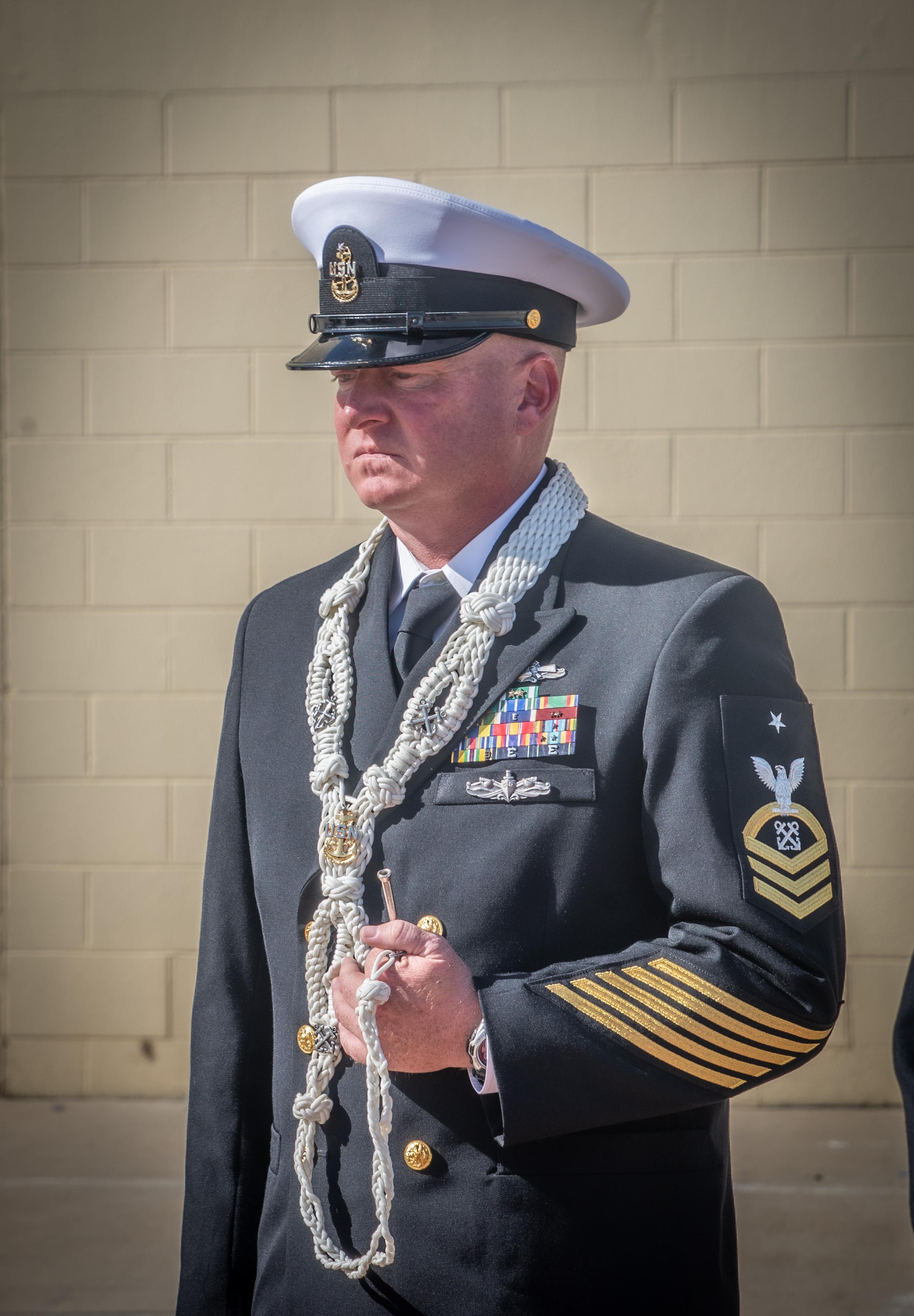 A sailor in formal attire wears medals and a ceremonial chain, radiating dignity.