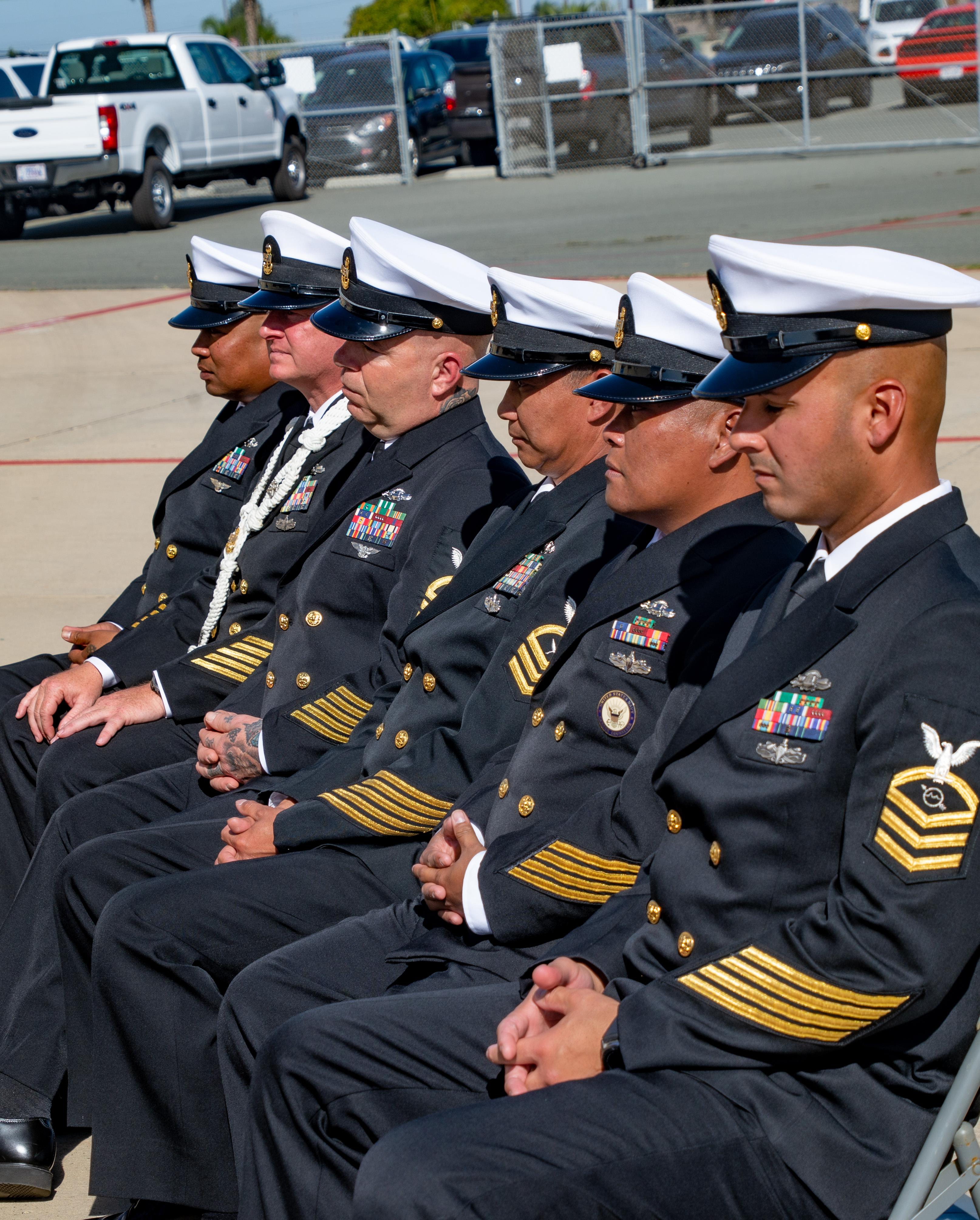 Uniformed officers sit in organized rows, engaged in a formal ceremony at a military base.