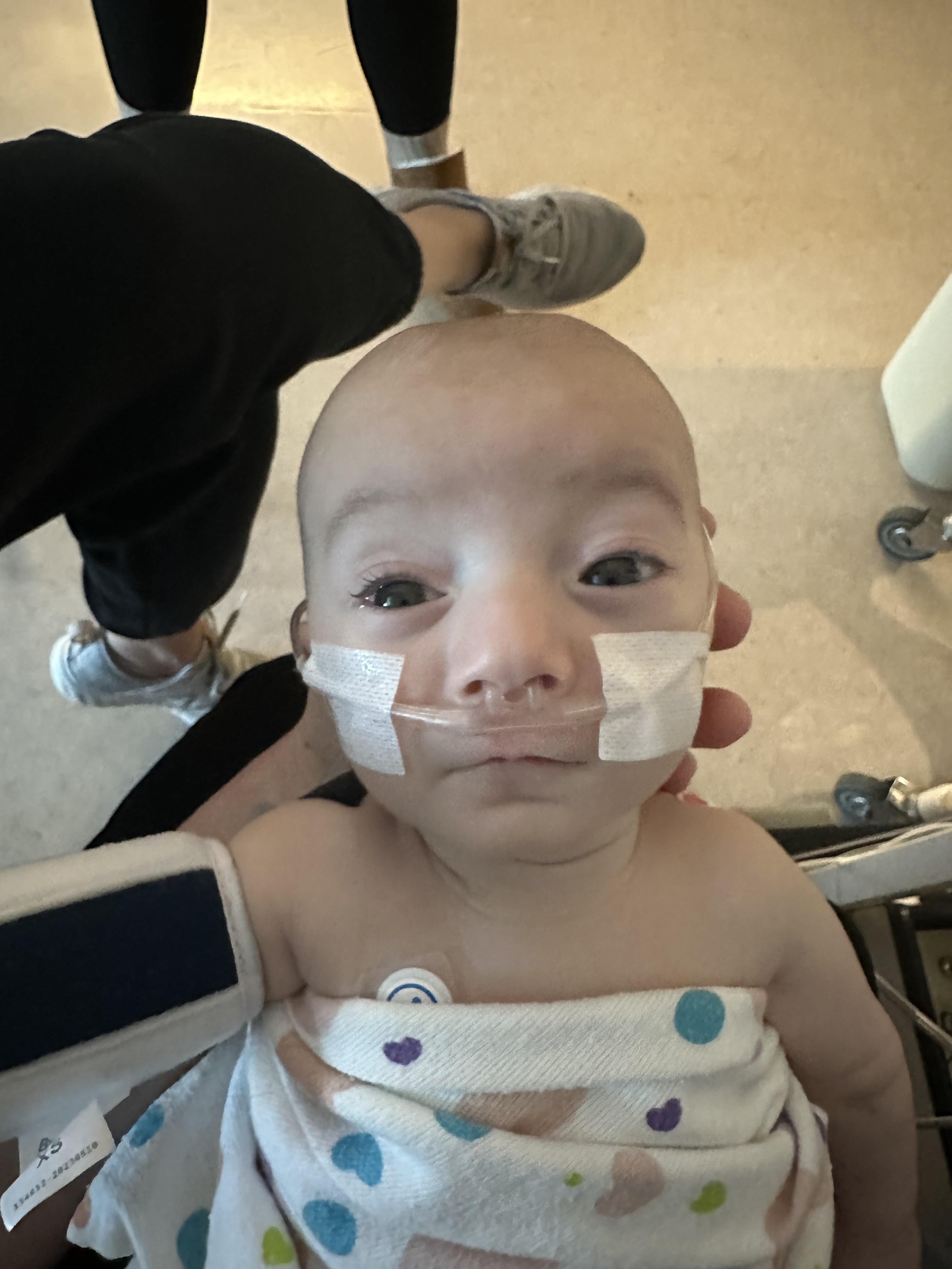 A baby is being examined by medical staff using equipment in a hospital.