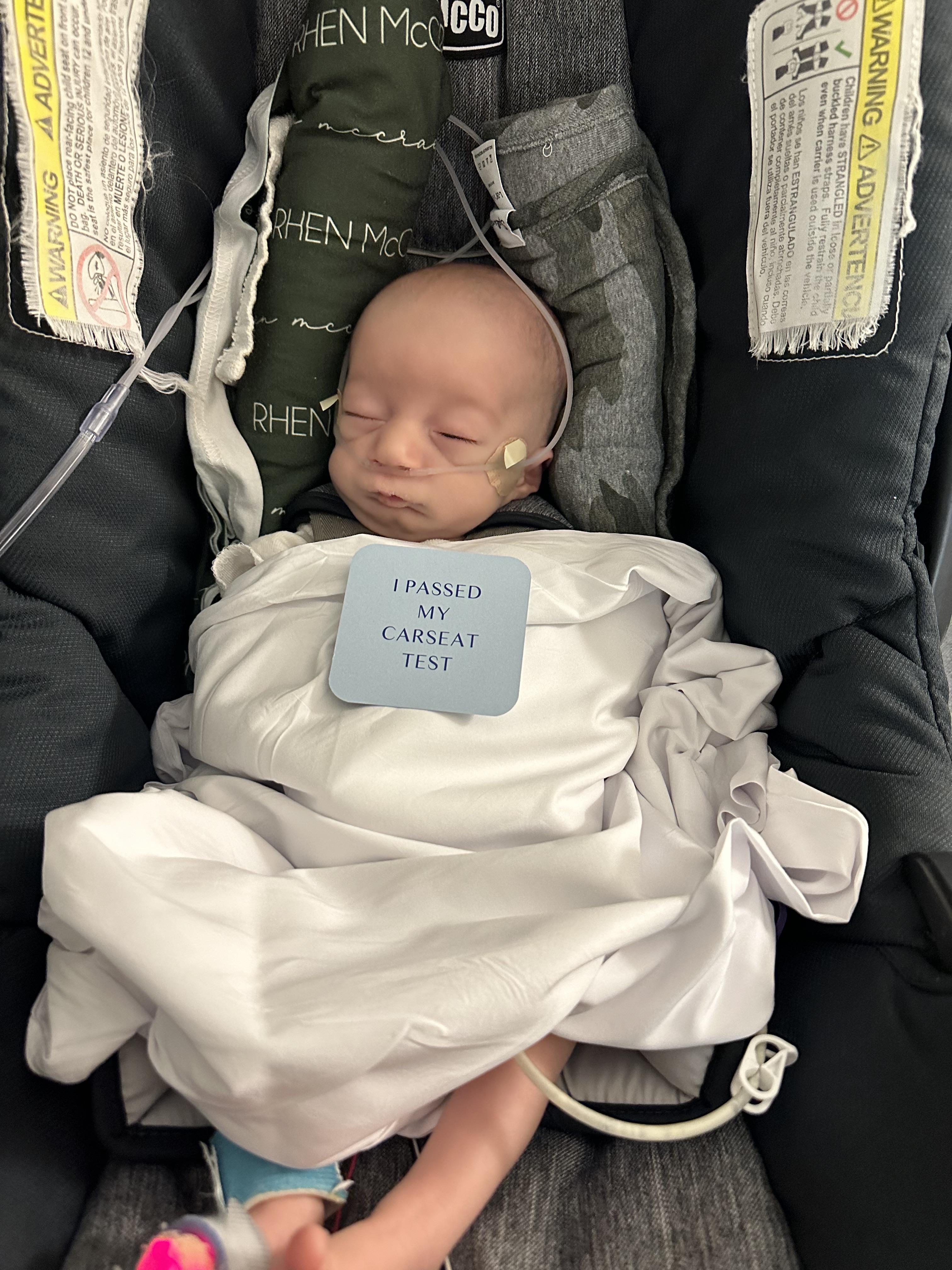 A newborn baby is comfortably secured in a safety seat while traveling with family.