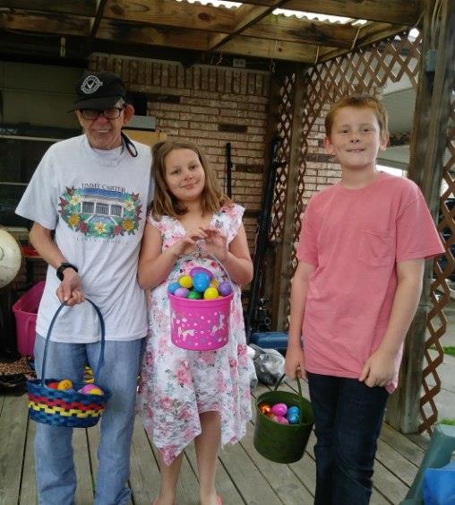 Three children happily pose with colorful baskets filled with eggs after a fun hunt.
