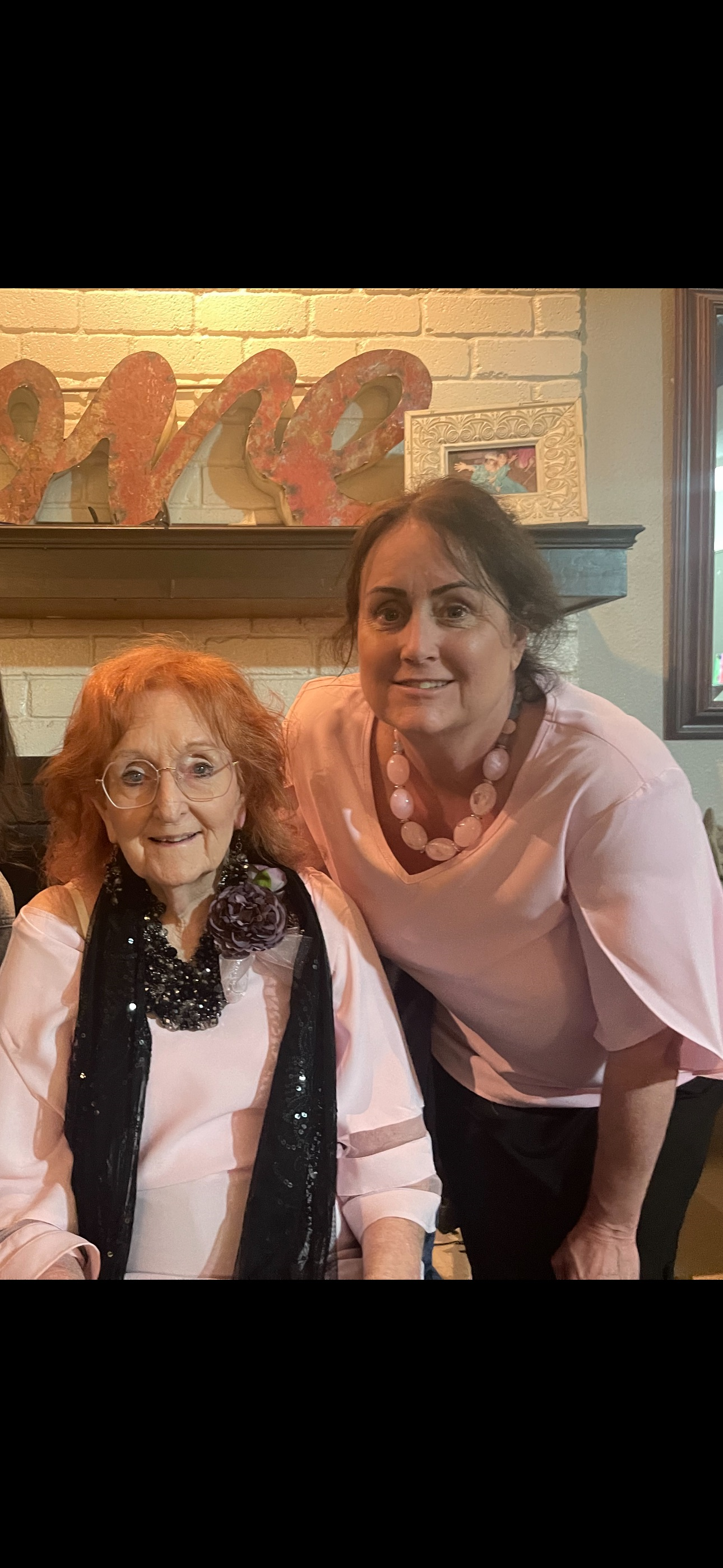 Two women, one elderly and one younger, share smiles while seated in a welcoming living room.