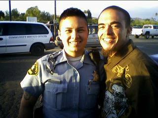 Two men pose together, smiling cheerfully in a parking lot as daylight fades, enjoying camaraderie.