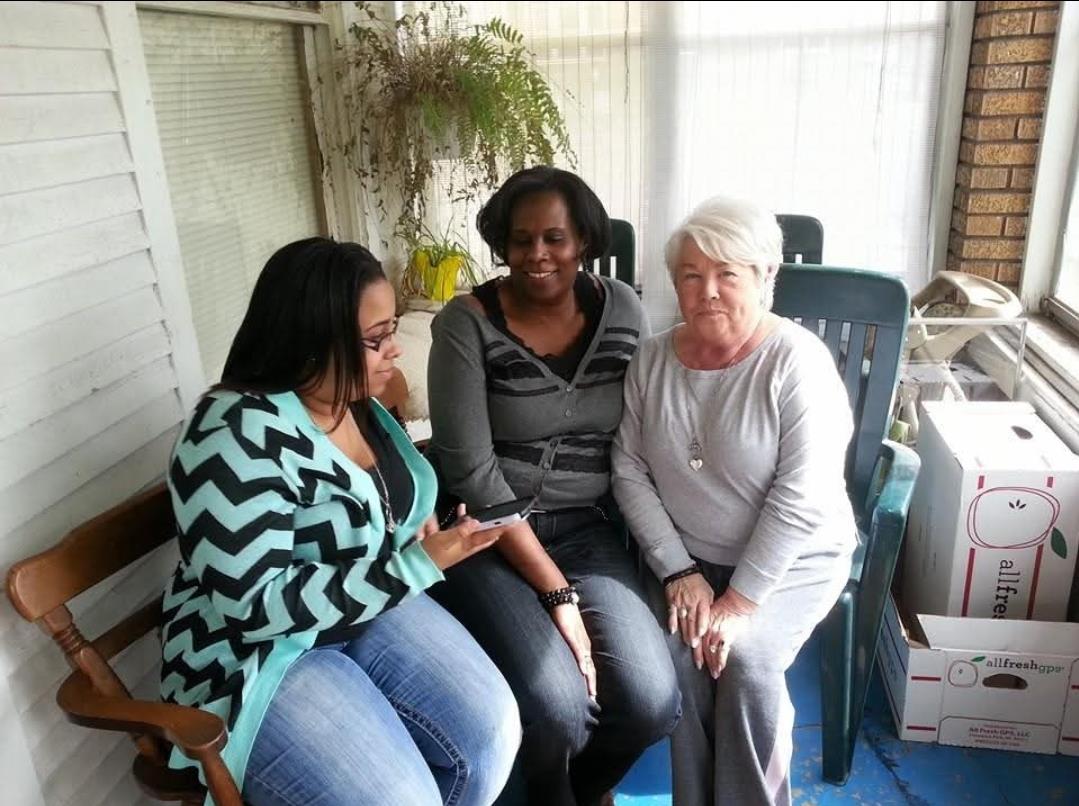 Three women are relaxing and conversing together in a cozy indoor setting, sharing laughter.