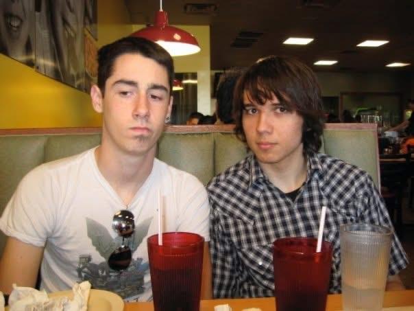 Two friends sit at a booth in a diner, both looking thoughtful while enjoying drinks.