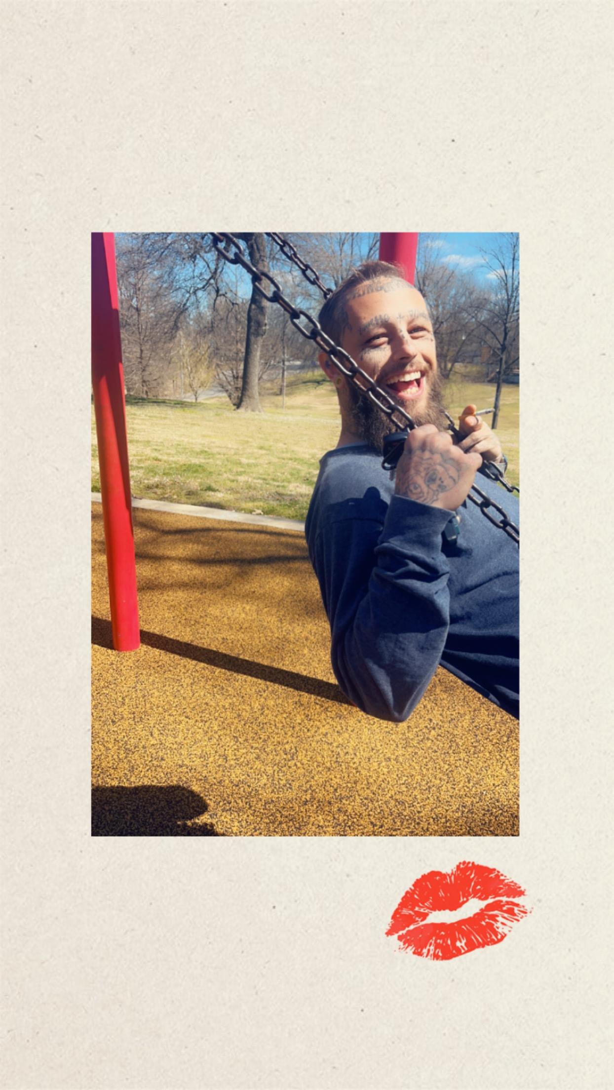 A man plays joyfully on a swing at a park, soaking in the sunlight and laughter around him.