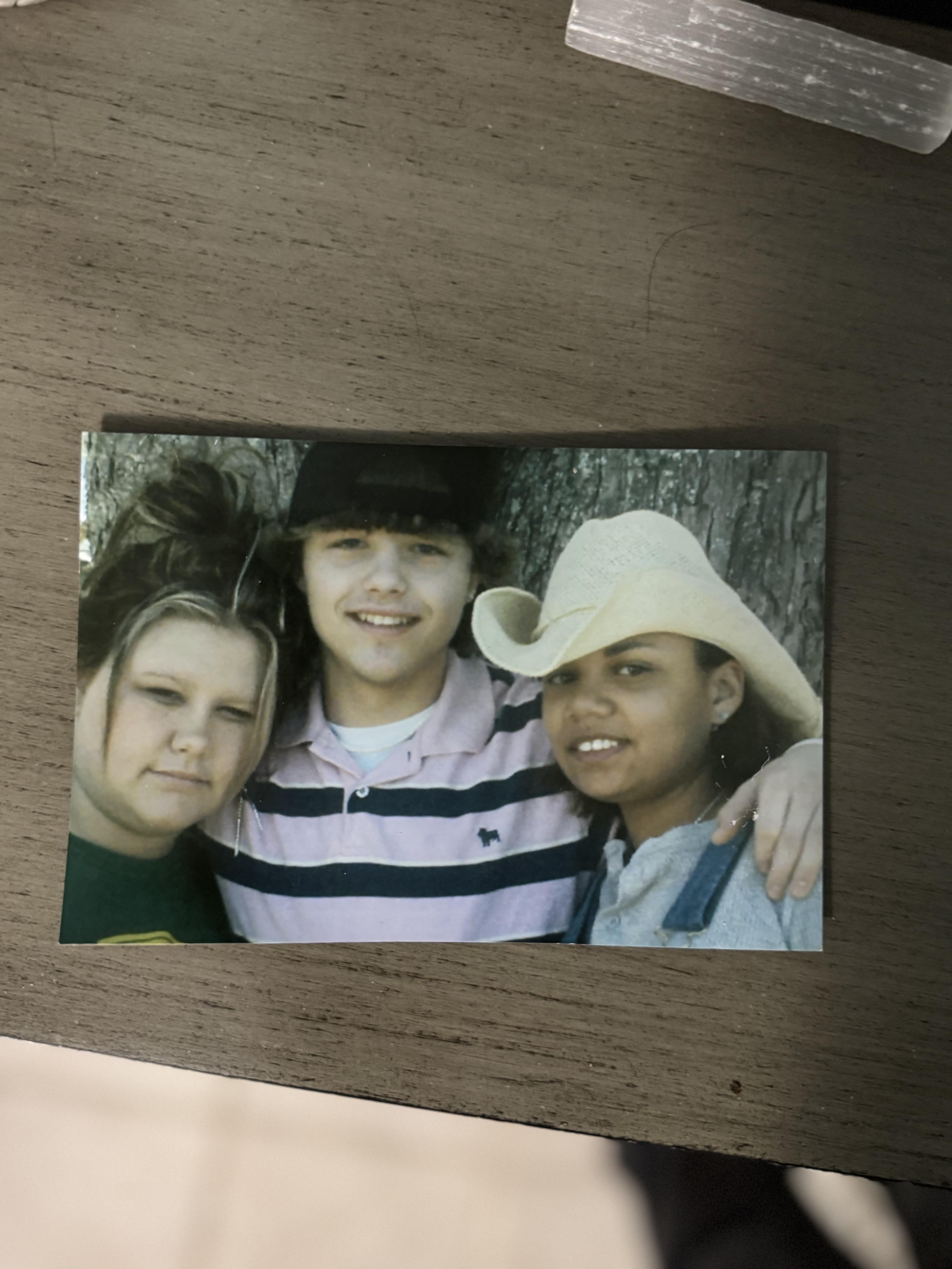 Friends stand close together, smiling brightly under the sun while showcasing their camaraderie.