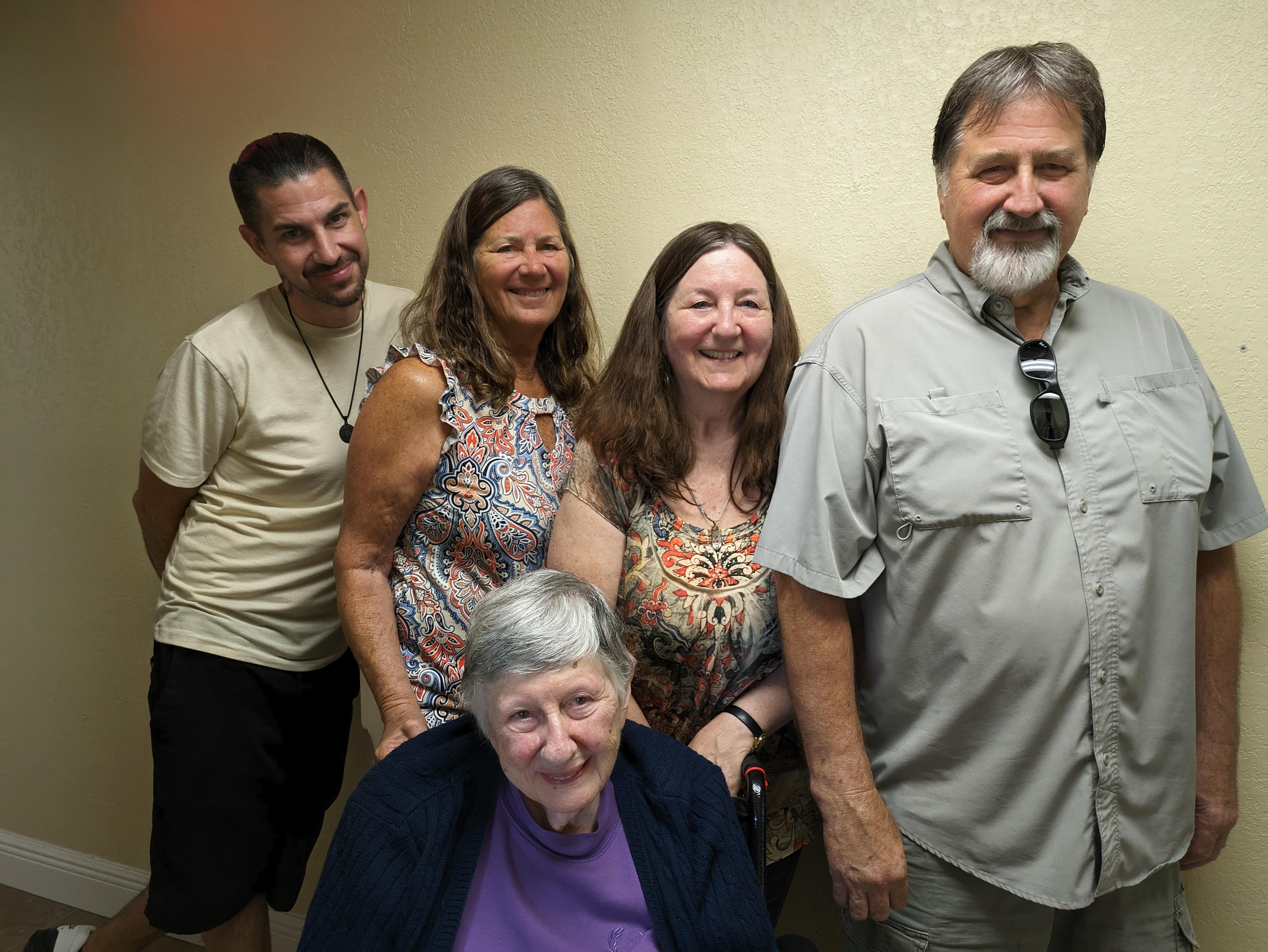 Five family members pose together in a cheerful indoor space, showcasing warm smiles.