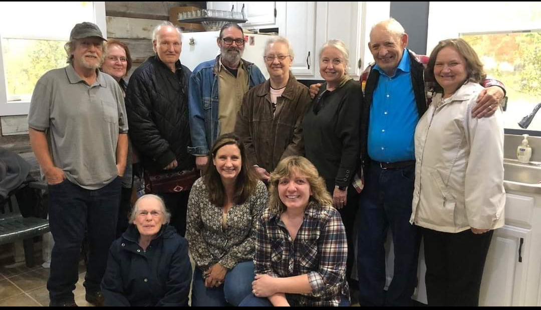 A warm gathering of friends and family inside a well-lit kitchen during autumn festivities.