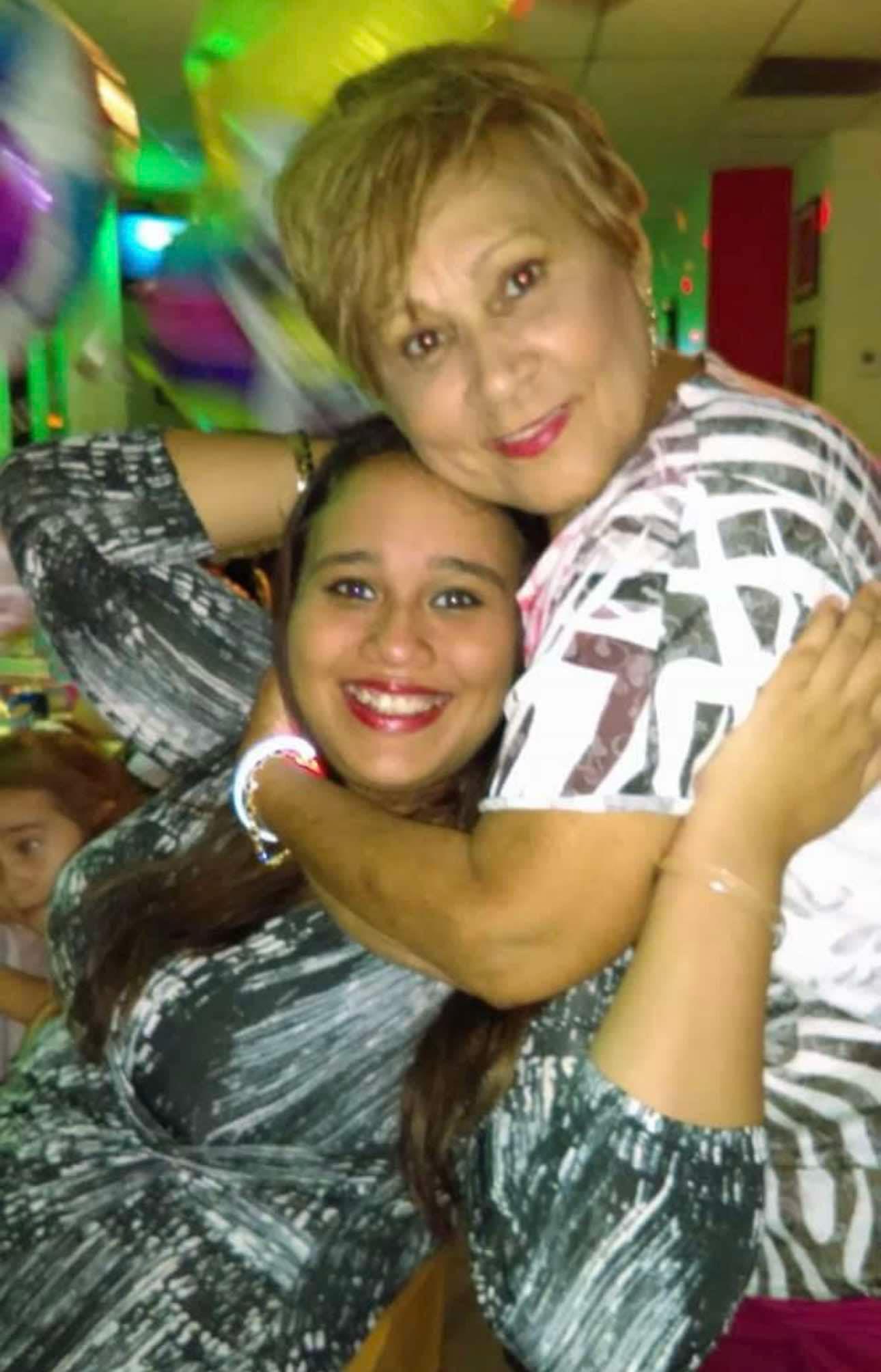 Two women embrace warmly while celebrating at a colorful gathering filled with joy.