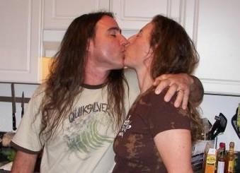 Two people lovingly embrace and kiss in a warm and inviting kitchen setting.