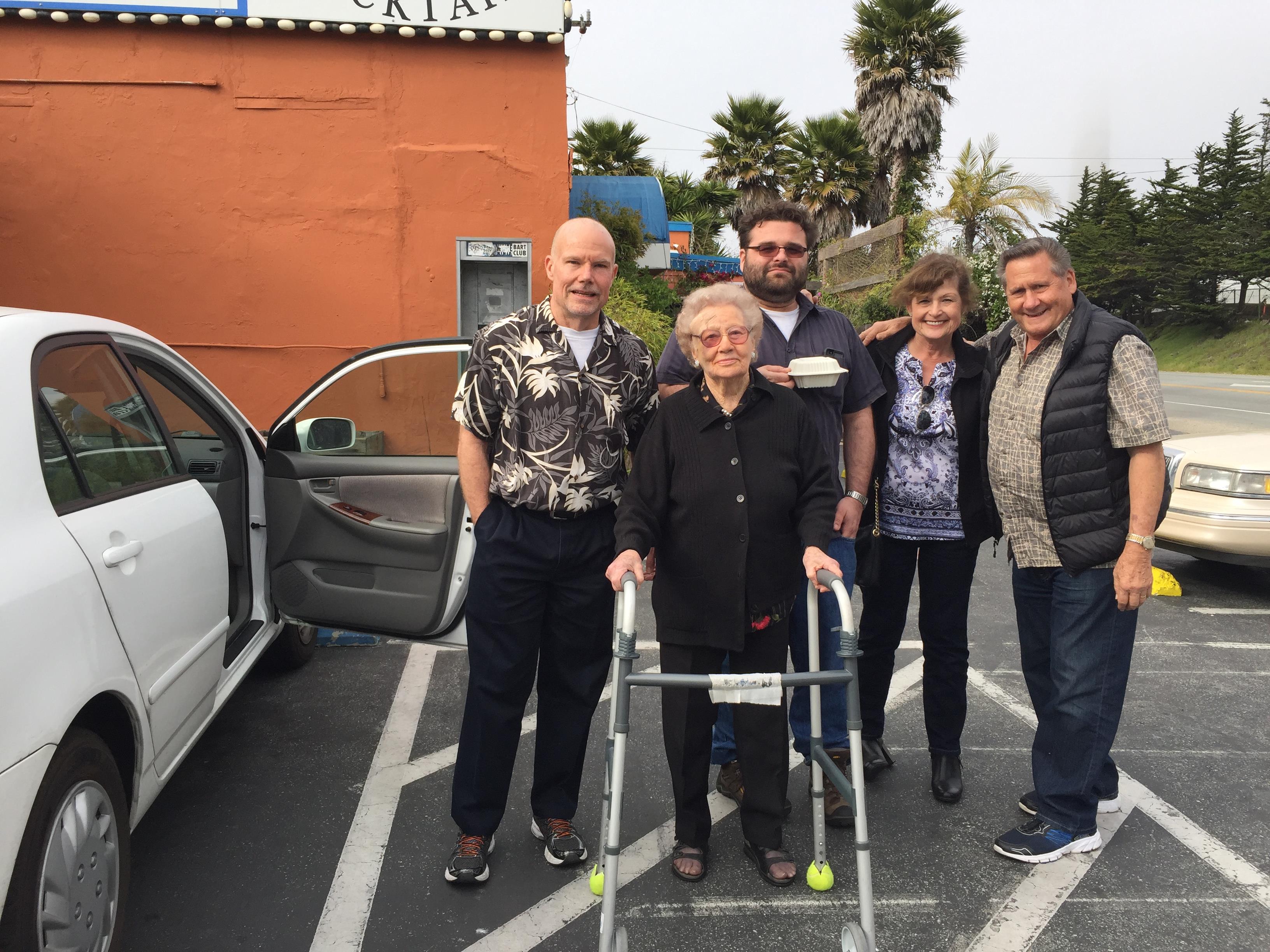 Group of five family members posing happily outside a restaurant, enjoying each other's company.