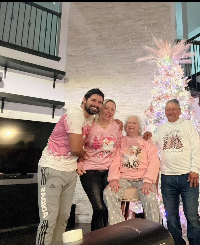 A family poses together in festive attire near a beautifully decorated Christmas tree.