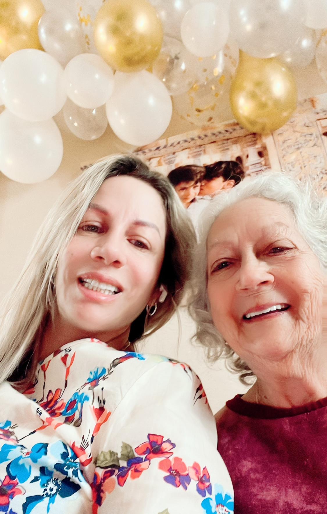 A woman and her grandmother are smiling widely, enjoying a festive family gathering filled with joy.