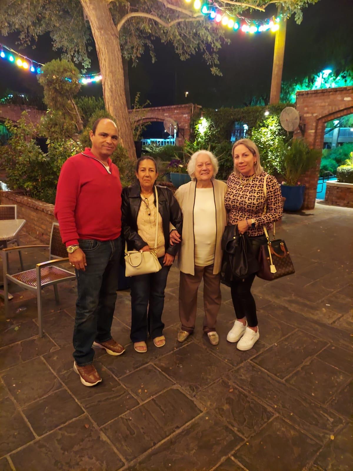 Friends gather in a charming garden at night, surrounded by warm lights and greenery.