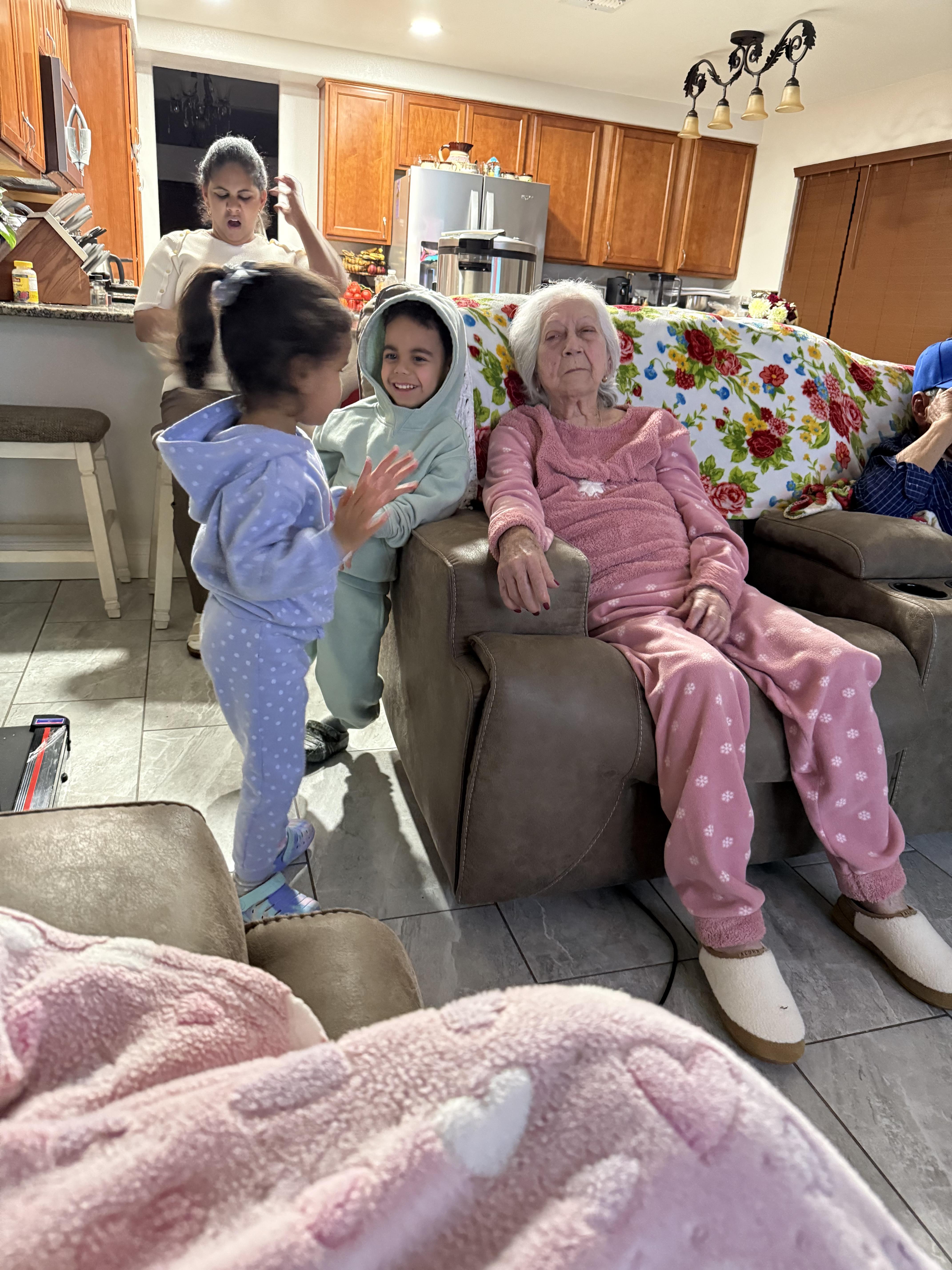 Children interact with their grandmother while relatives relax in a warm, inviting space.