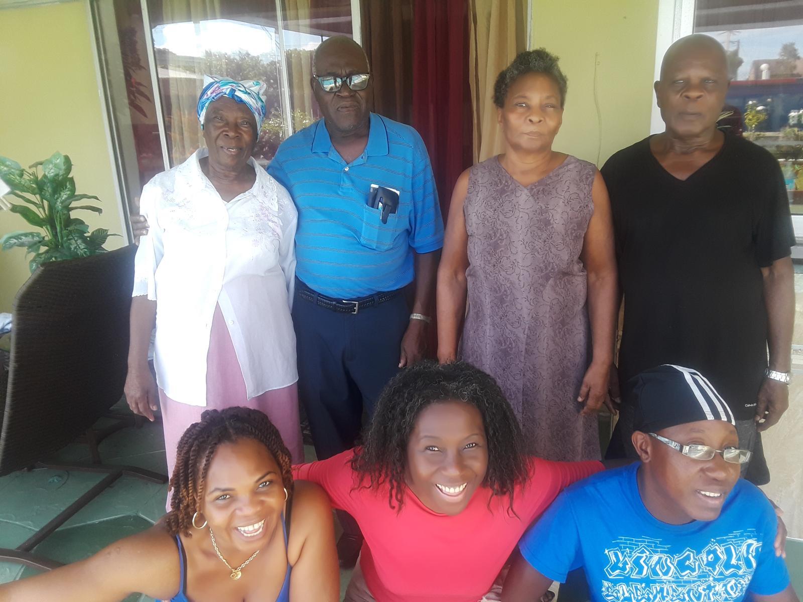 Group of family members joyfully posing together at a home during a sunny afternoon.