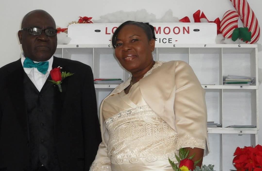 Happily married couple poses together in formal clothing adorned with flowers in a cozy setting.