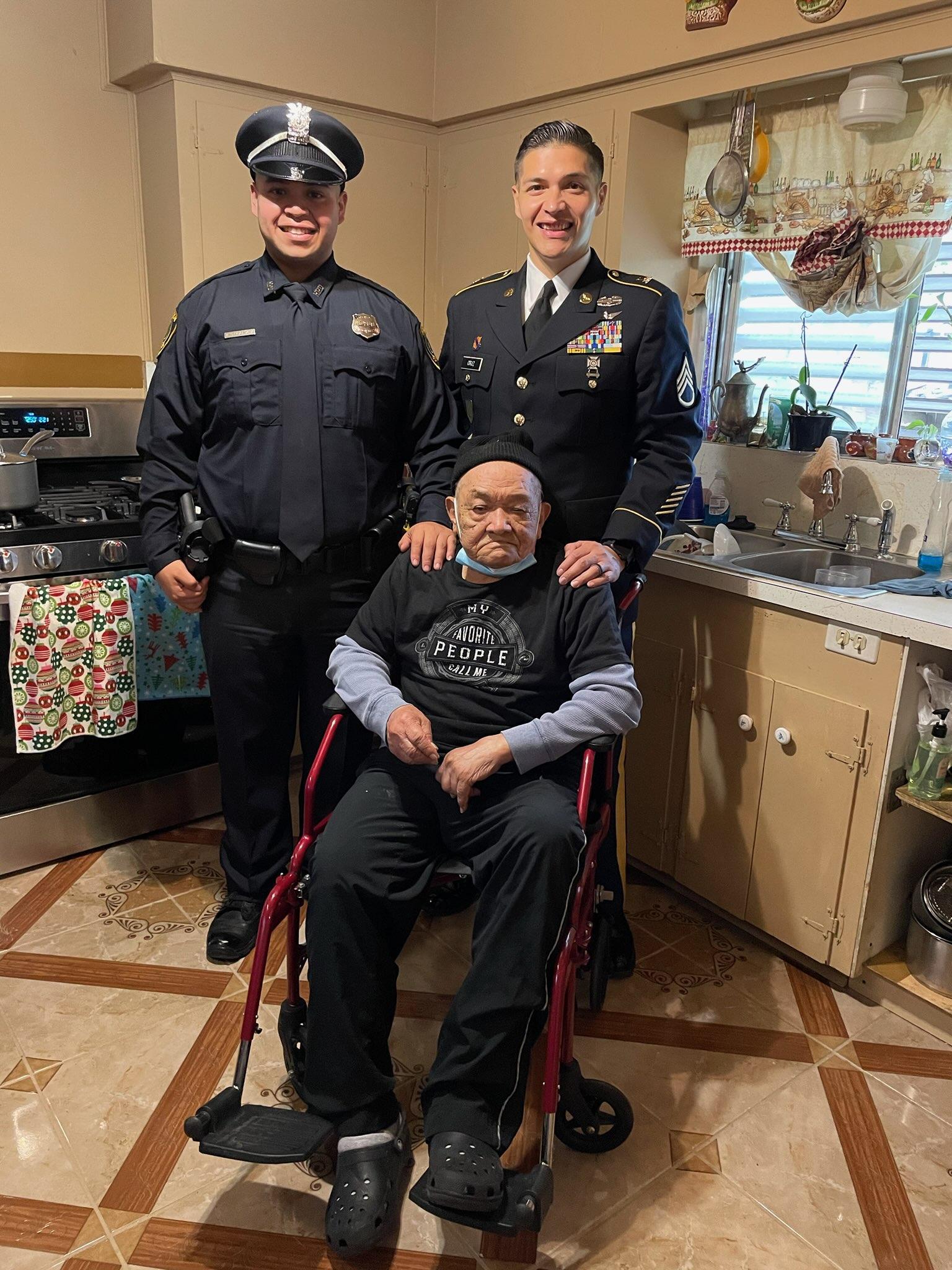 Two police officers smile alongside an elderly man in a cozy kitchen setting, celebrating community.