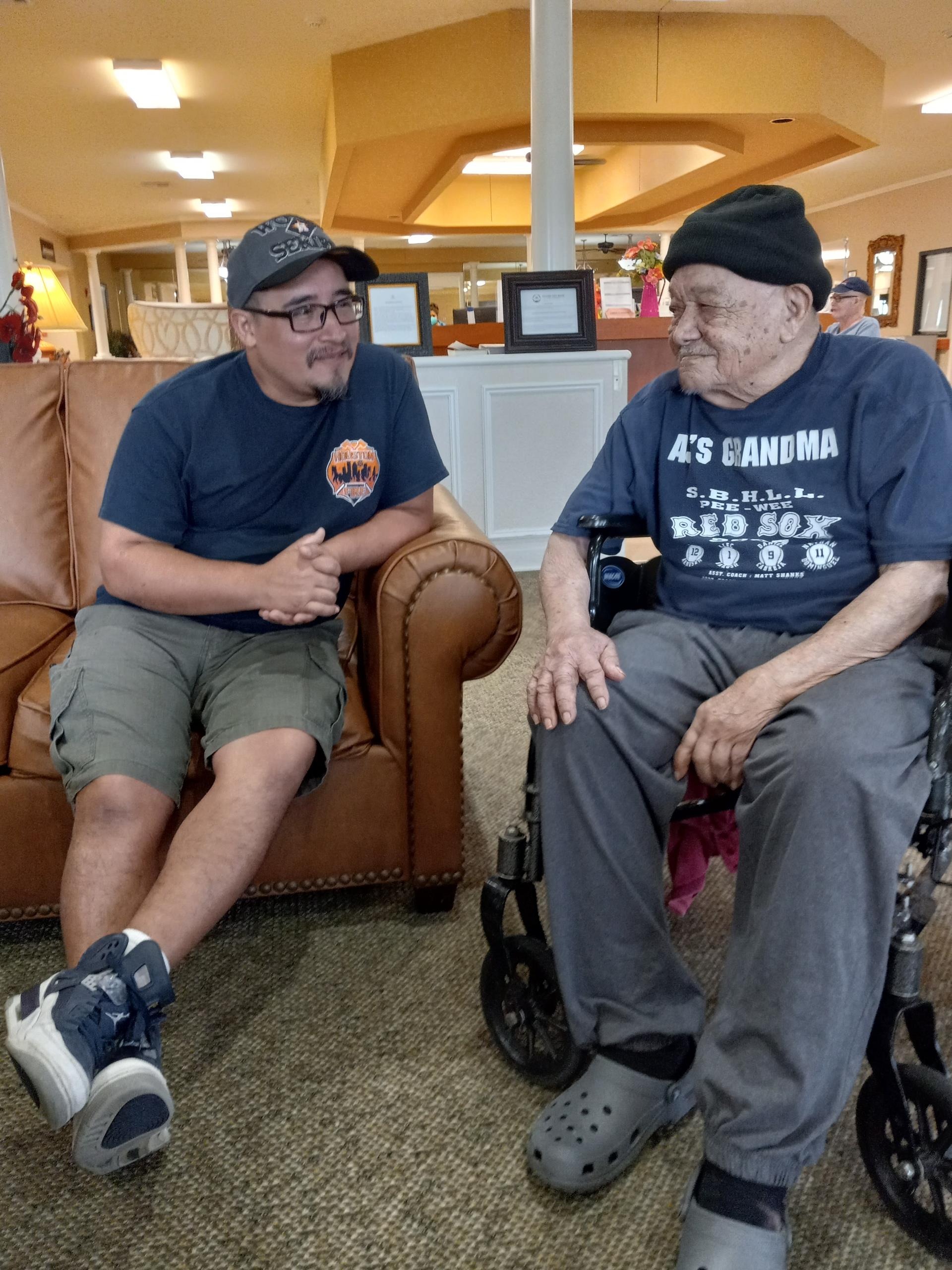 Two men are chatting comfortably on a couch in a community center.