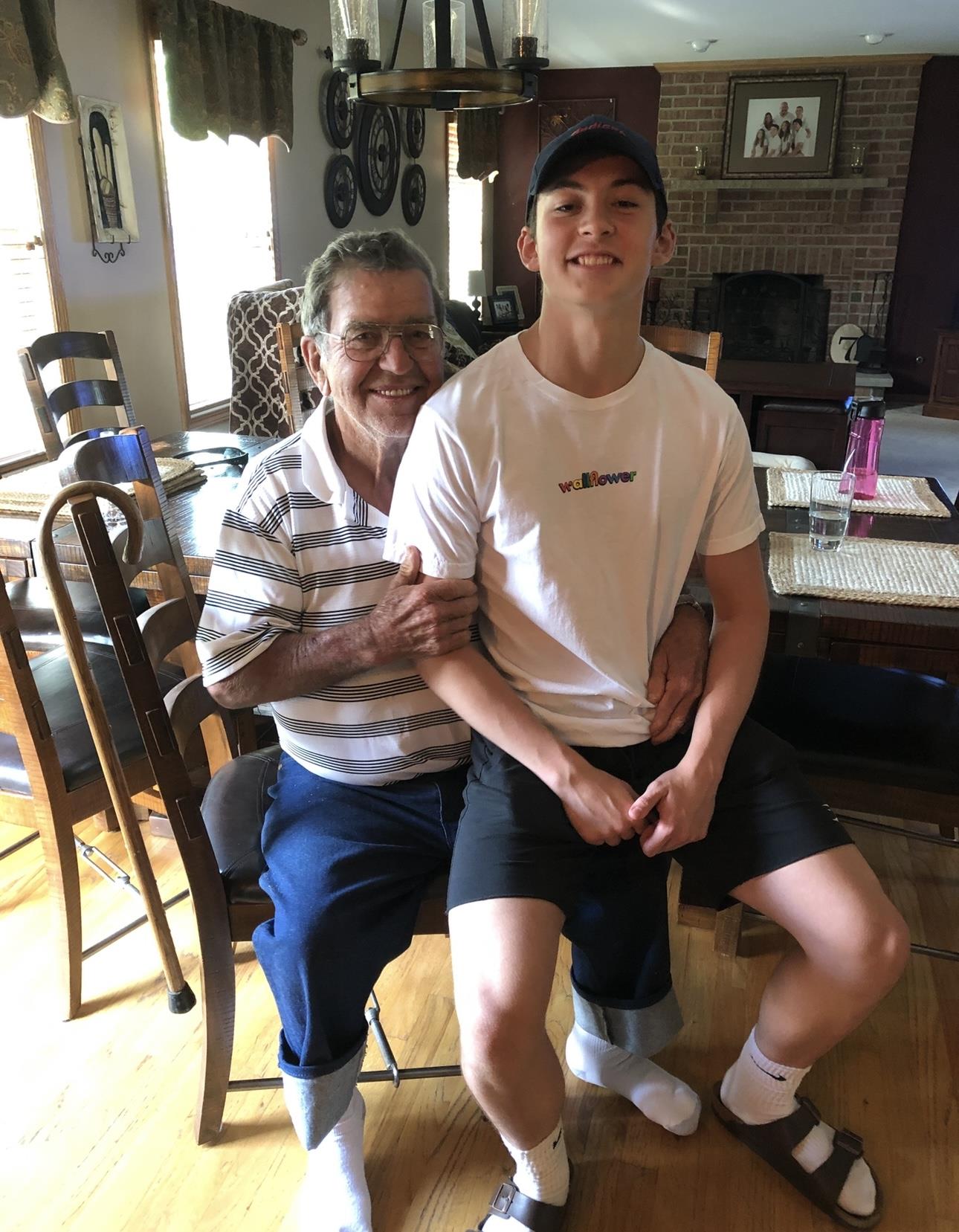 Two relatives smile warmly while sitting together at a table in a comfortable home.