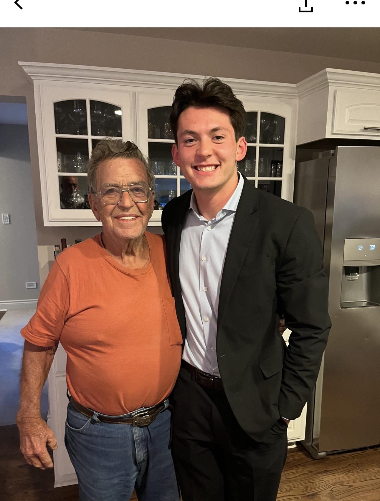 Two men pose for a cheerful photo in a well-lit kitchen, enjoying a family moment.